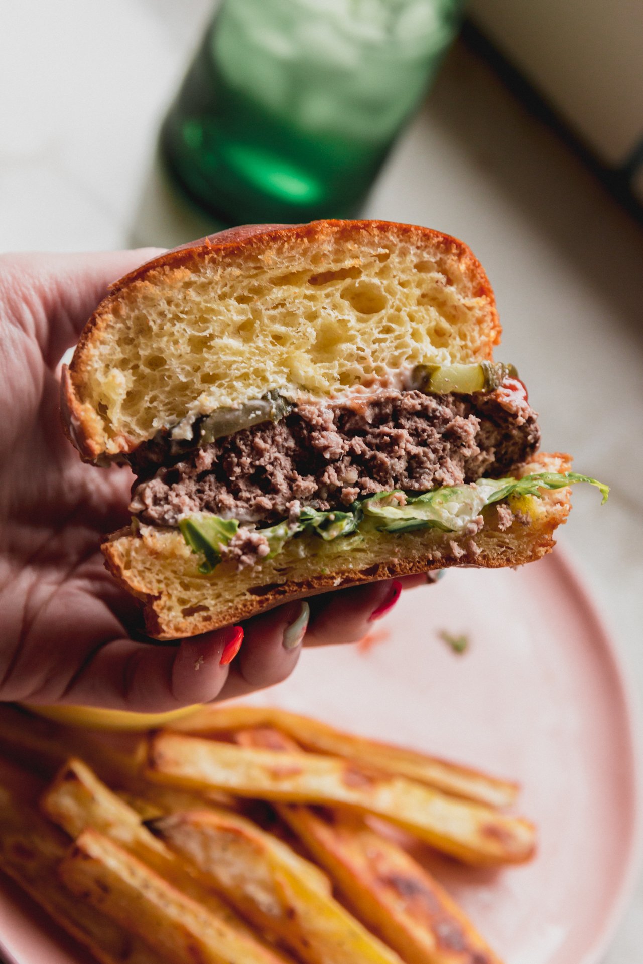 The burger after being cooked on a bun with toppings and cut in half.