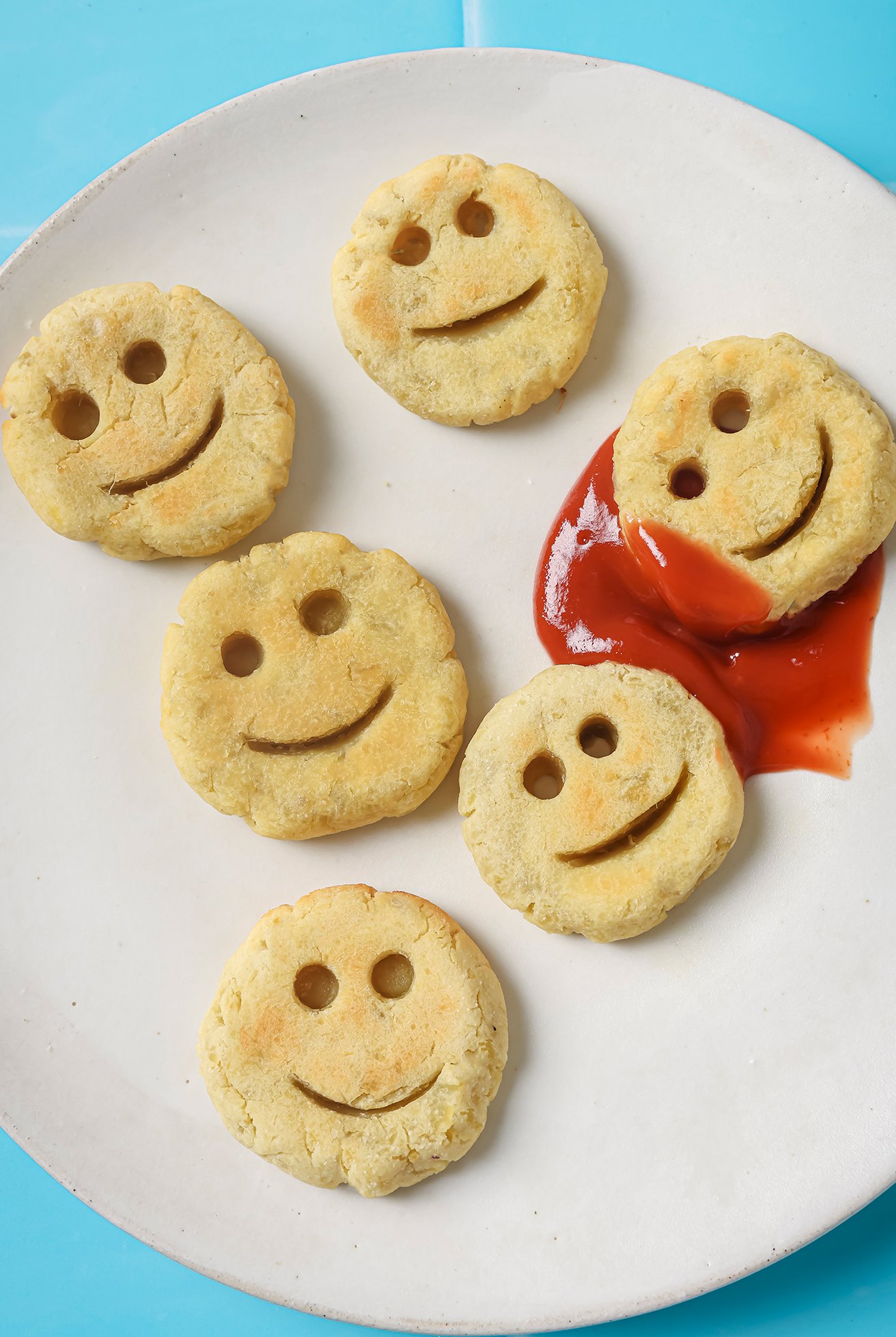 Sweet potato smiley fries on a white plate with ketchup.