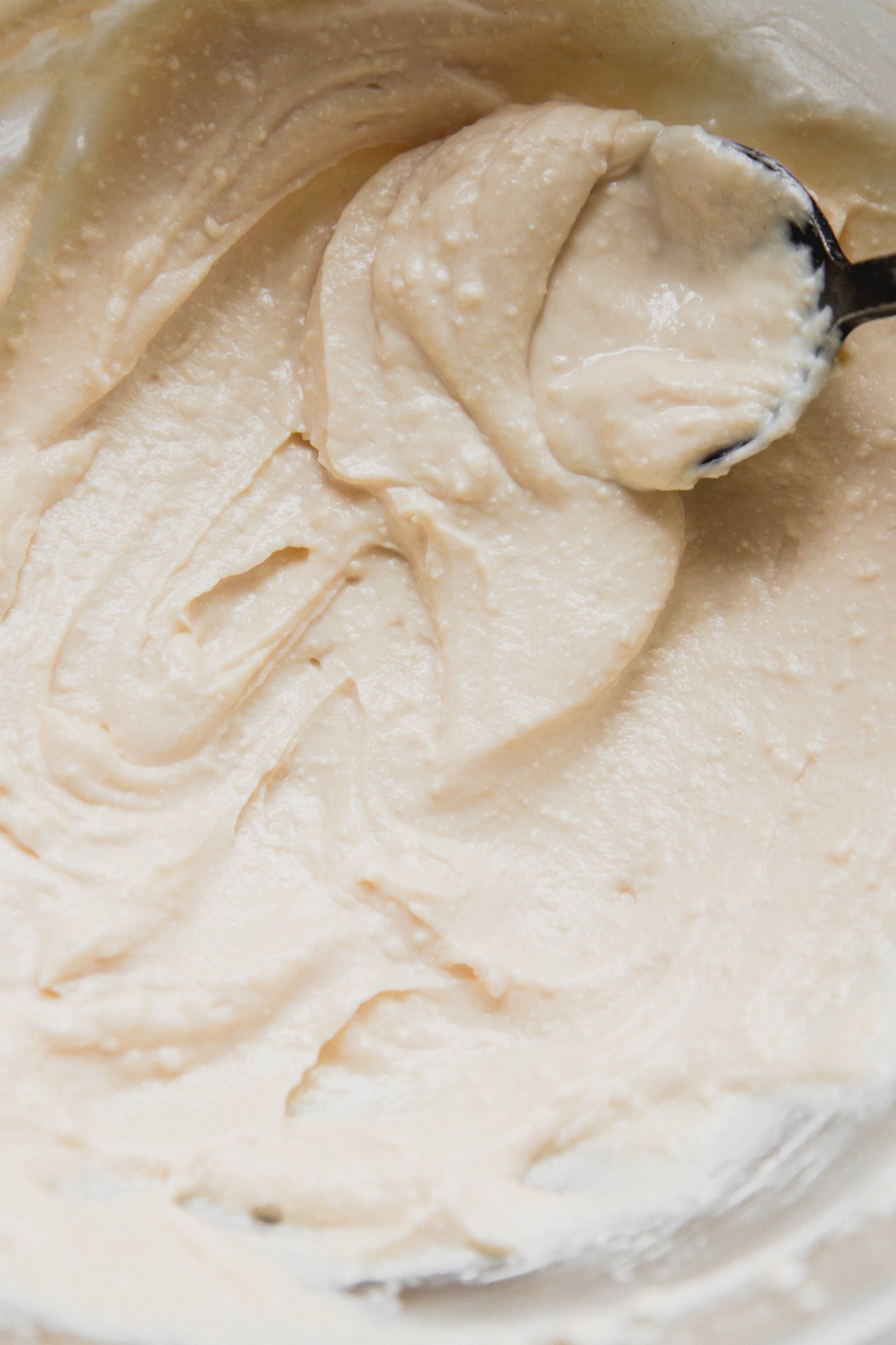 A spoon smoothing the cannoli cream after mixing. 