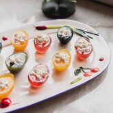 Sliced jello deviled eggs of a decorate white plate, topped off with whipped cream.