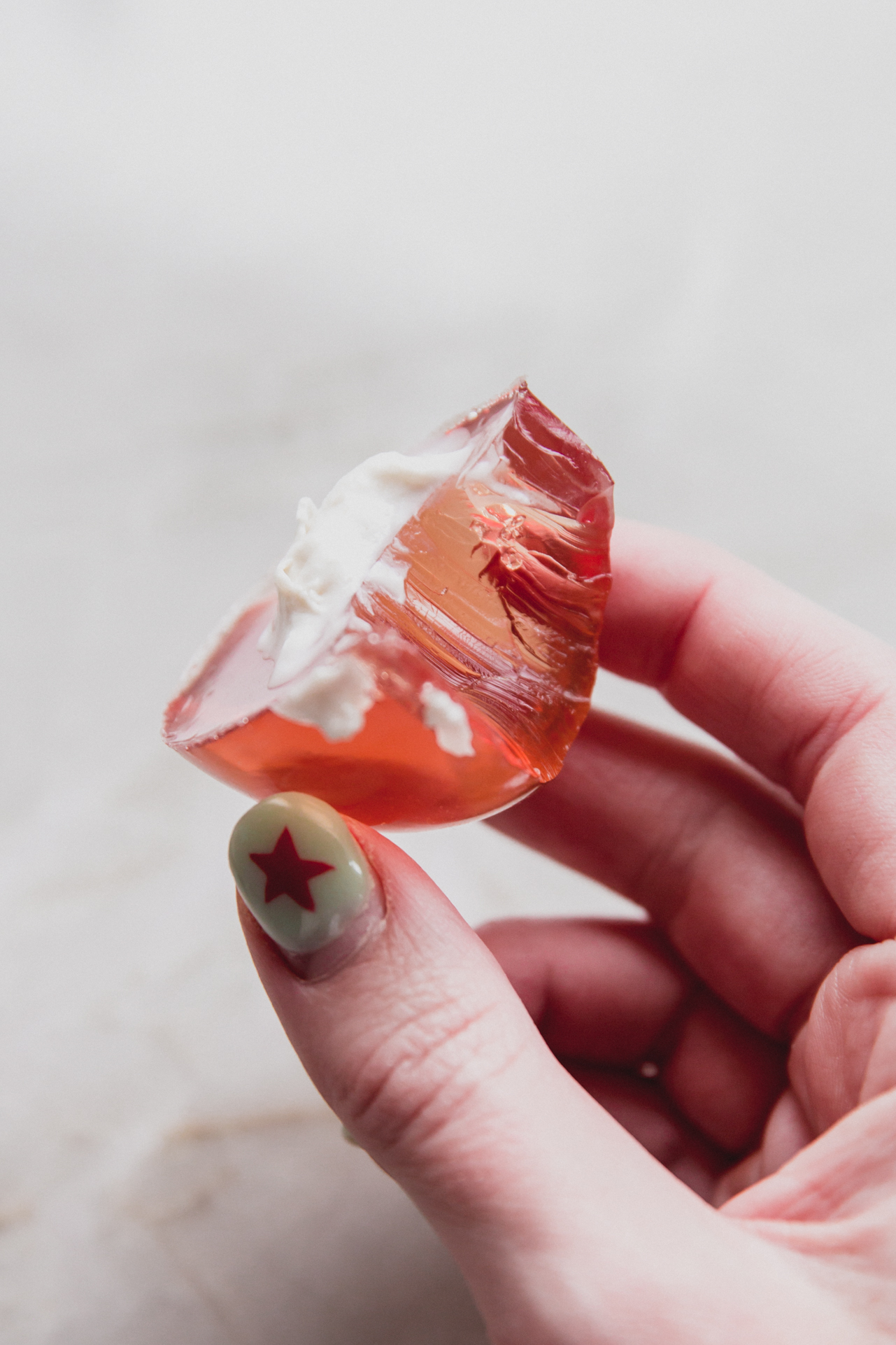 A hand holding a jello deviled egg with a bite taken out of it.