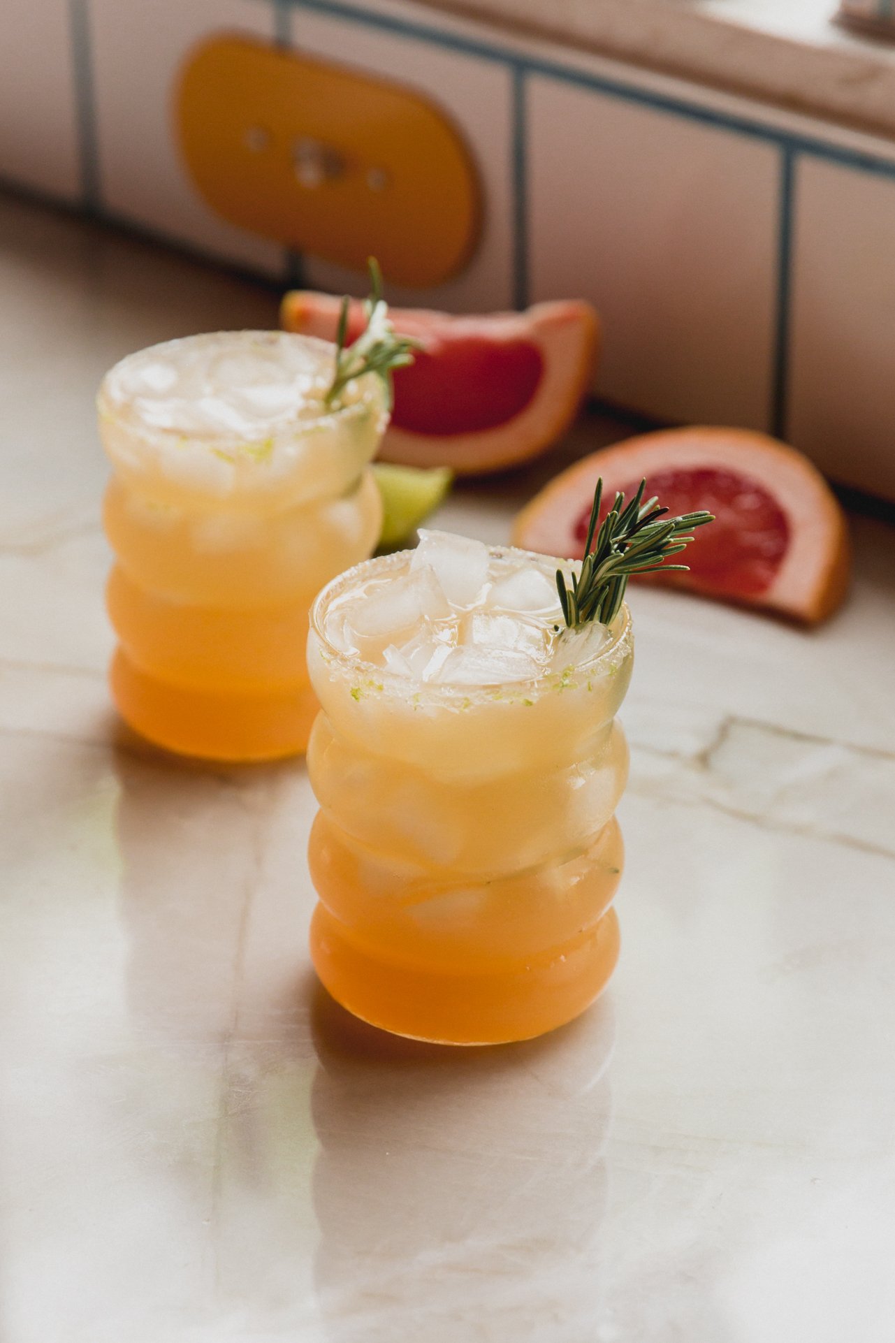 Two healthier grapefruit palmoa mocktails on the counter.