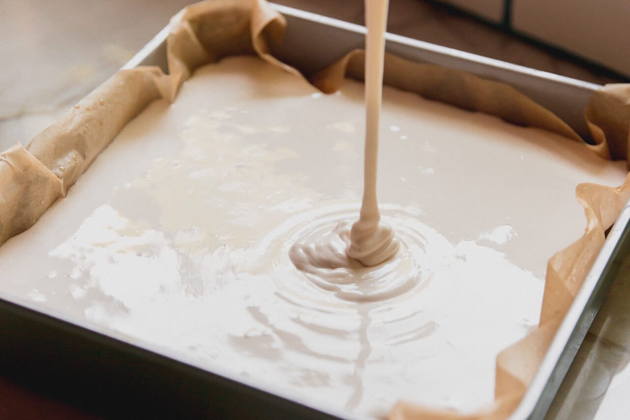 Pouring the marshmallow layer into the pan over the crust.