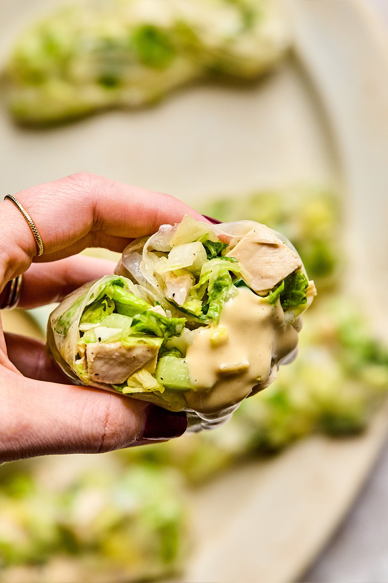 Caesar rice paper roll cut in half with some dressing. 