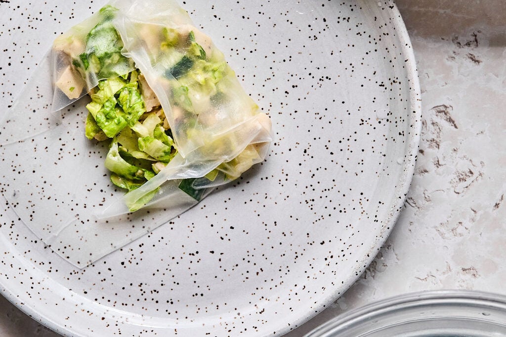 Rice paper being rolled with salad.