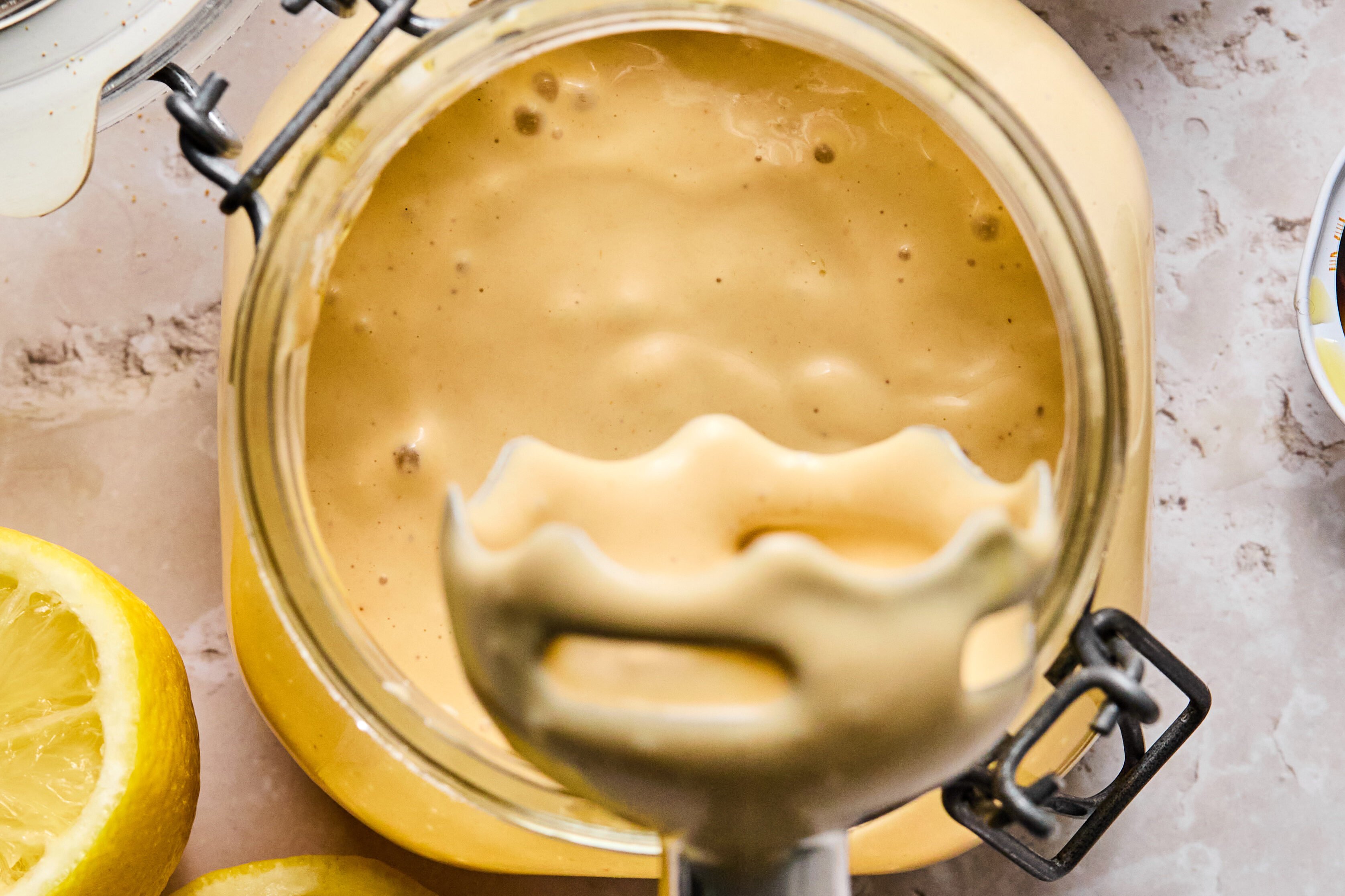 An immersion blender after blending the caesar dressing in a jar.