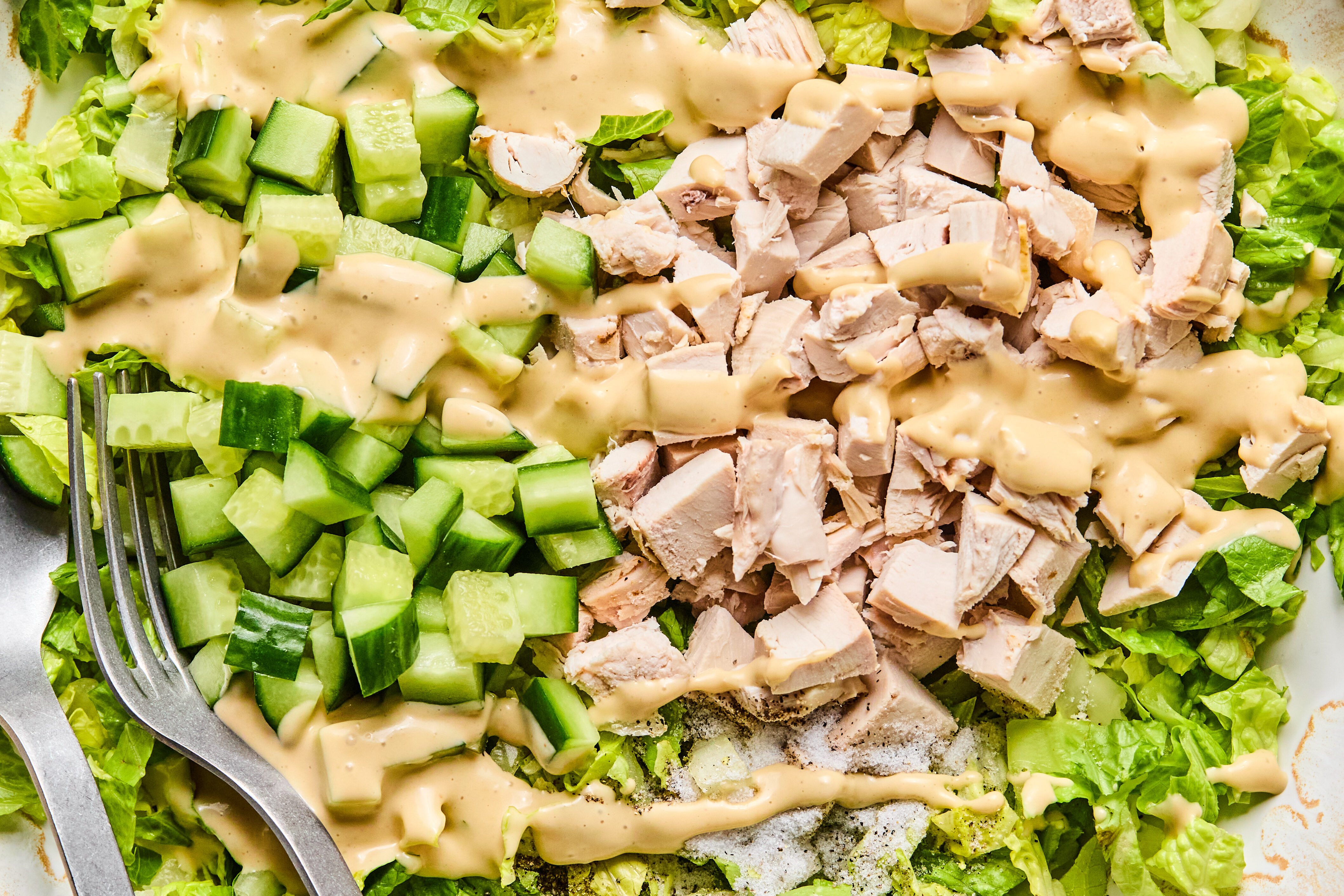The chicken caesar salad with dressing poured on top before mixing.