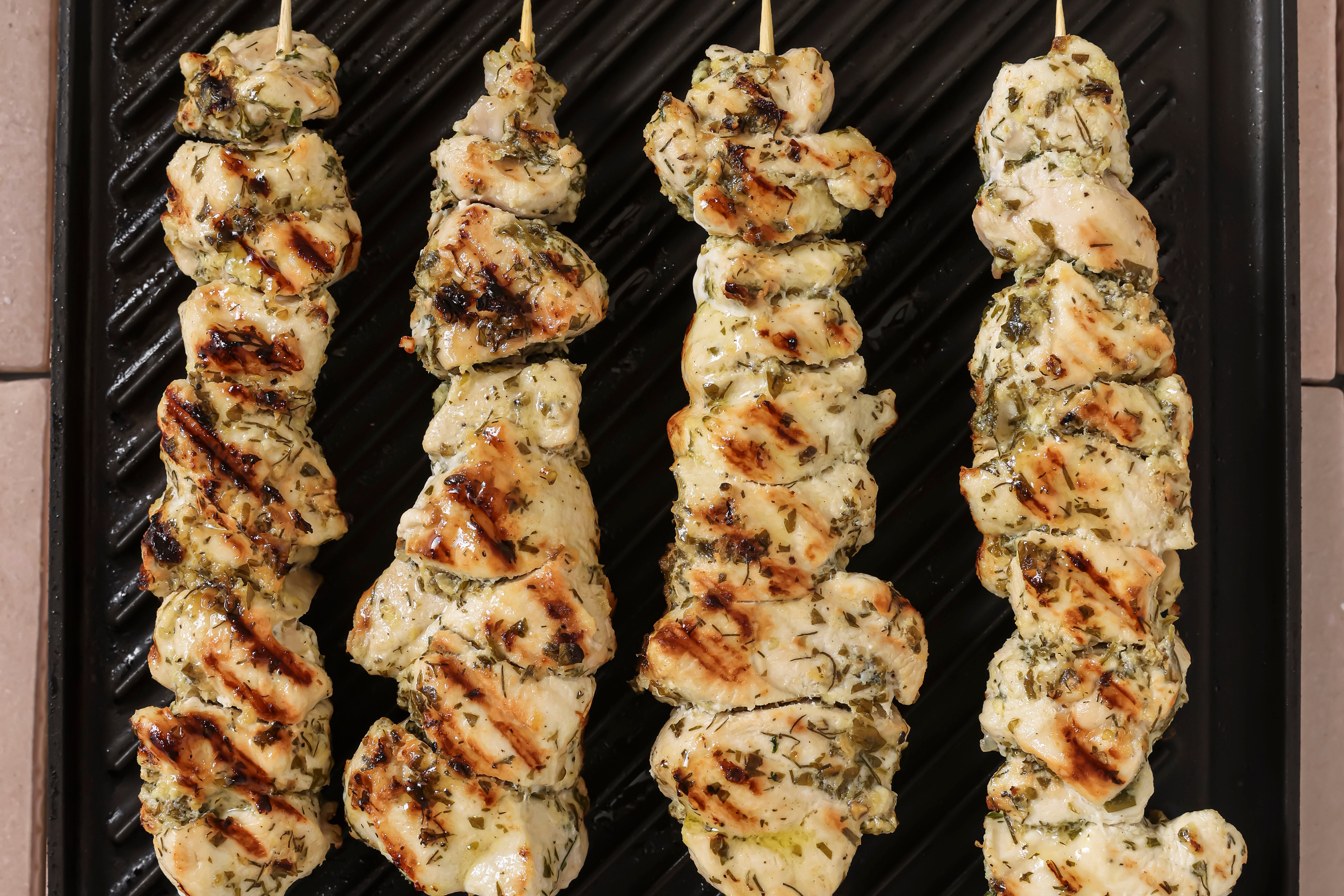 Chicken souvlaki cooking on an indoor grill.