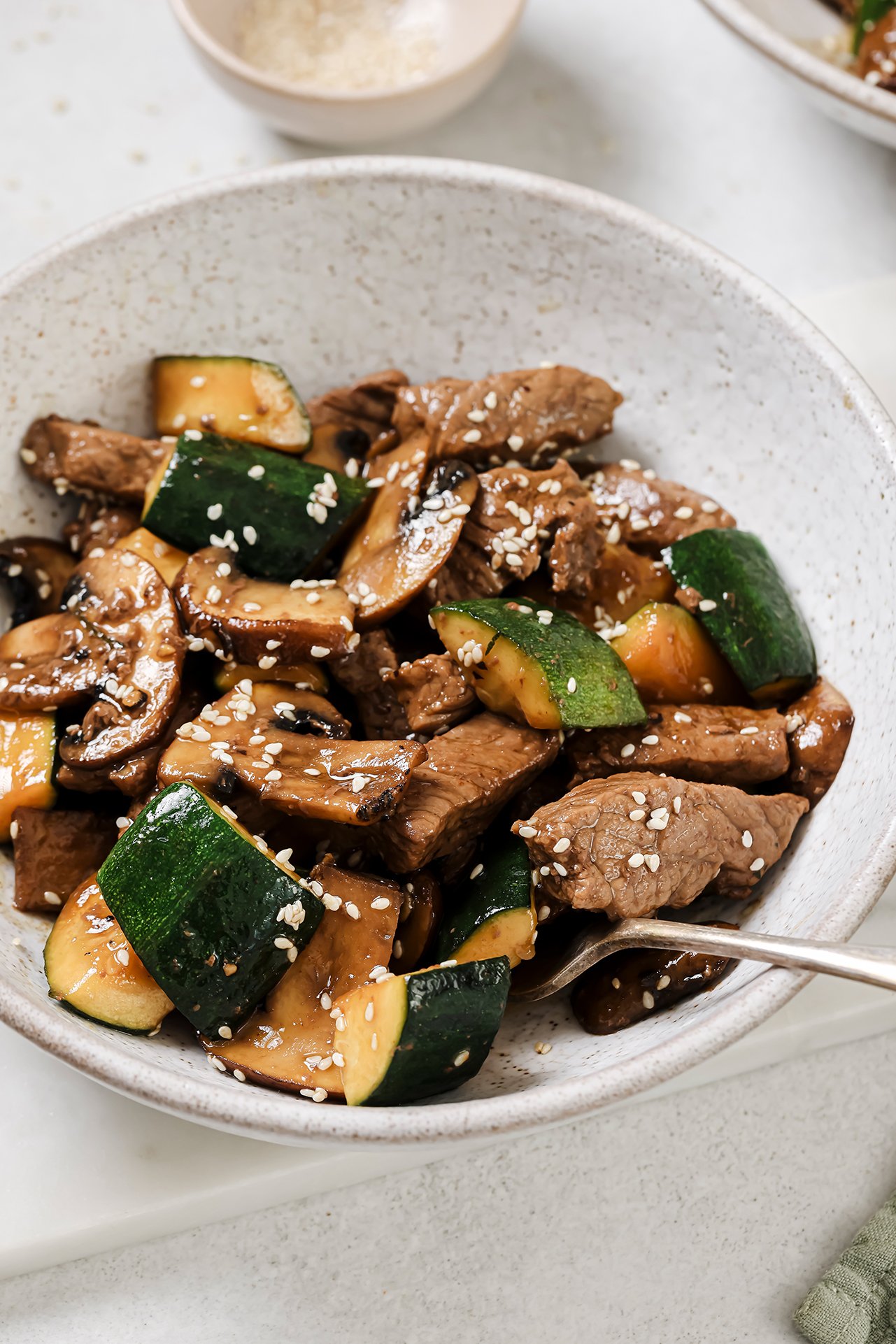 A bowl of hibachi steak bites with zucchini and mushrooms, ready to be eaten.
