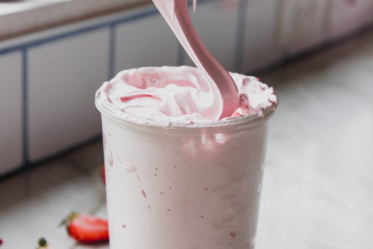 Pouring strawberry marshmallow fluff into a jar.
