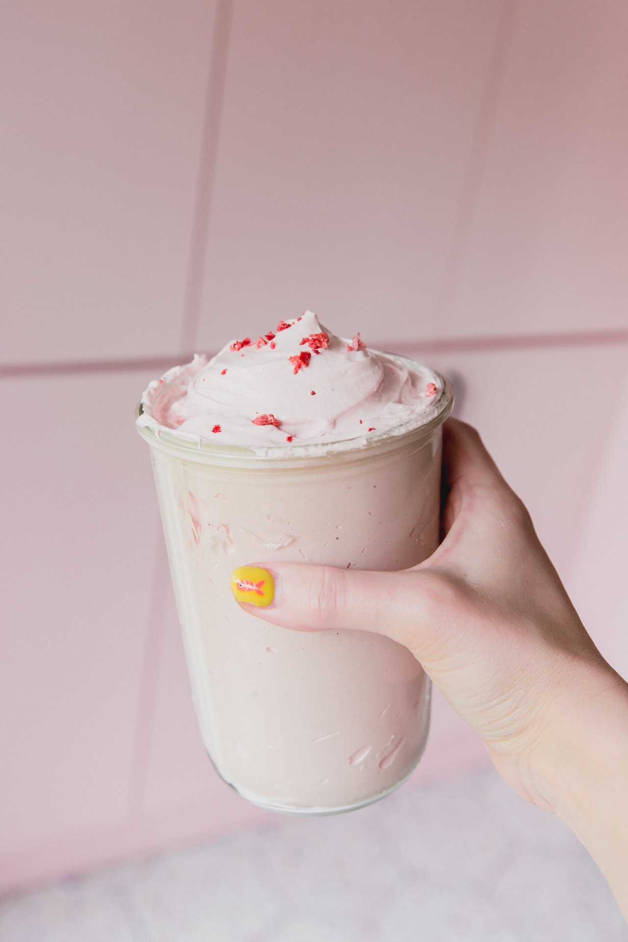 A hand holding a jar of strawberry marshmallow fluff.