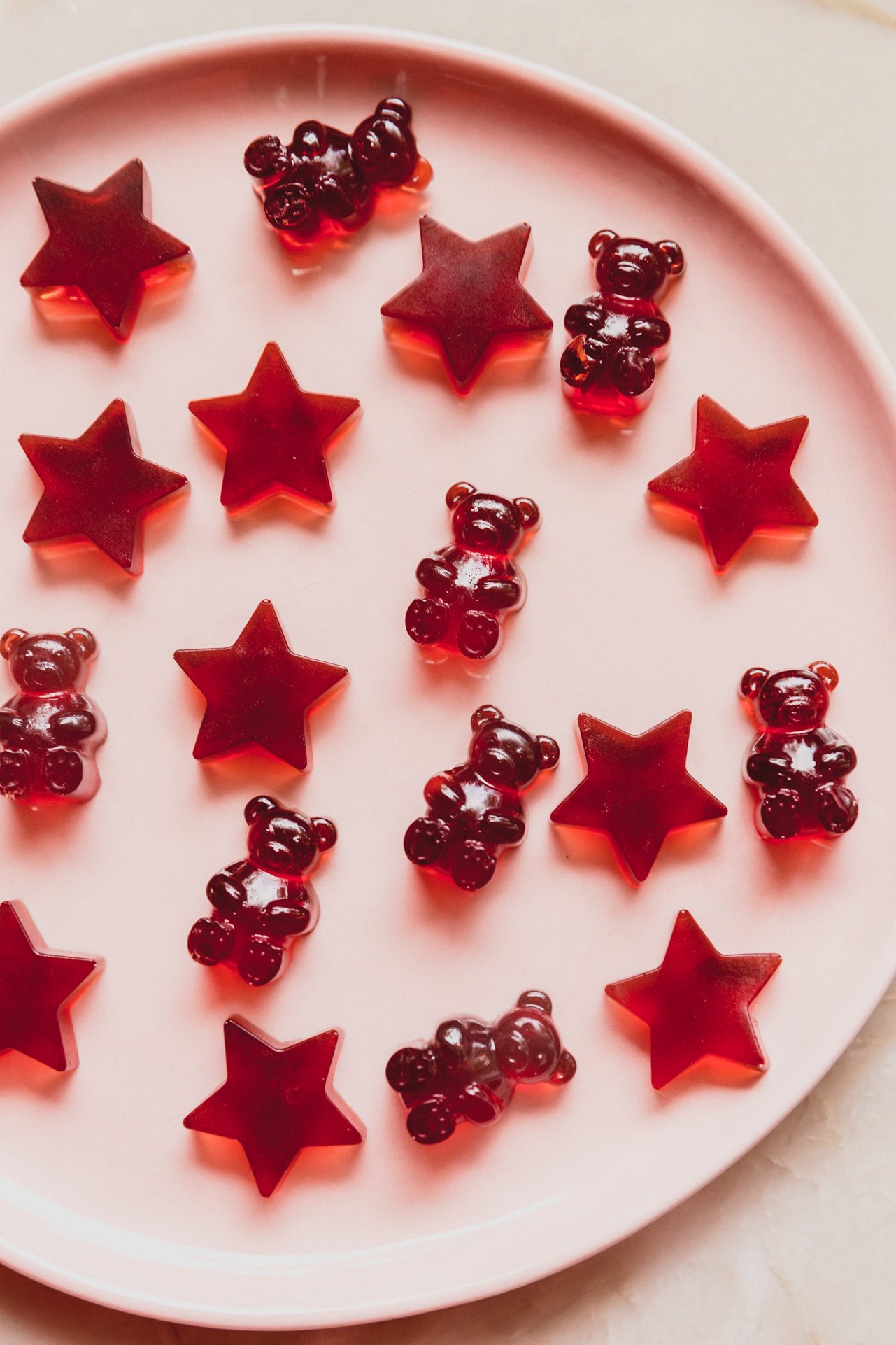 Tart cherry gummies on a pink plate.