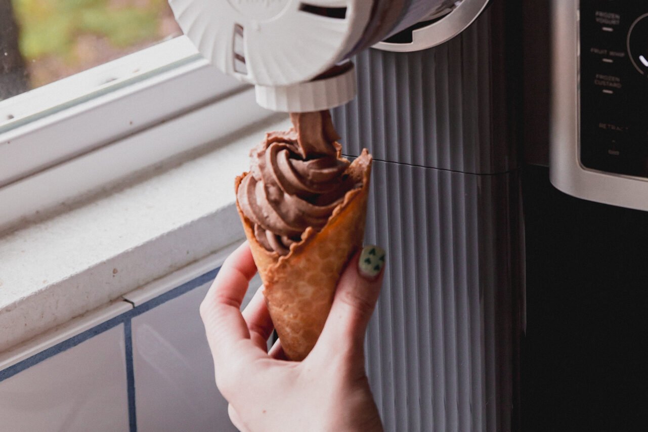 The ninja creami swirl attachment putting the chocolate protein ice cream into a cone.