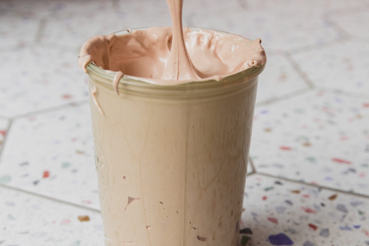 Marshmallow fluff being put into a glass container. 