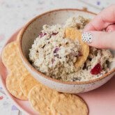 Chicken salad in a bowl with a cracker being dipped in.