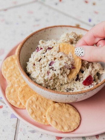 Chicken salad in a bowl with a cracker being dipped in.
