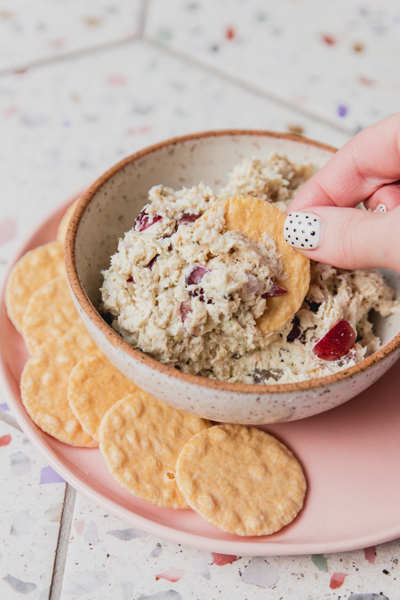 Chicken salad in a bowl with a cracker being dipped in.