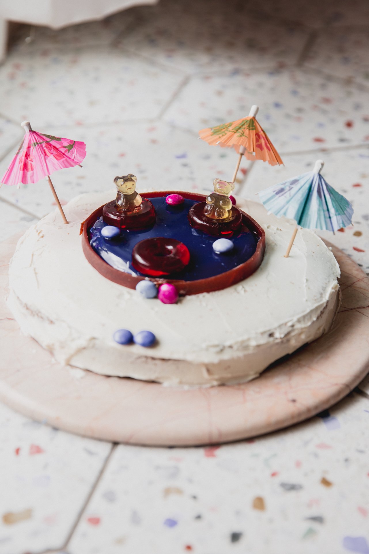 Swimming pool cake topped with paper umbrellas.
