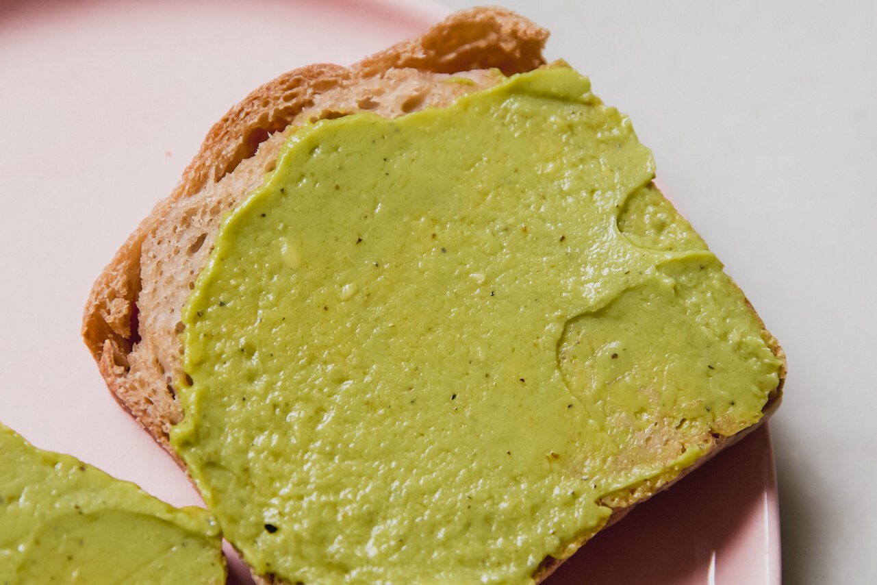 A piece of toast with avocado spread on top.