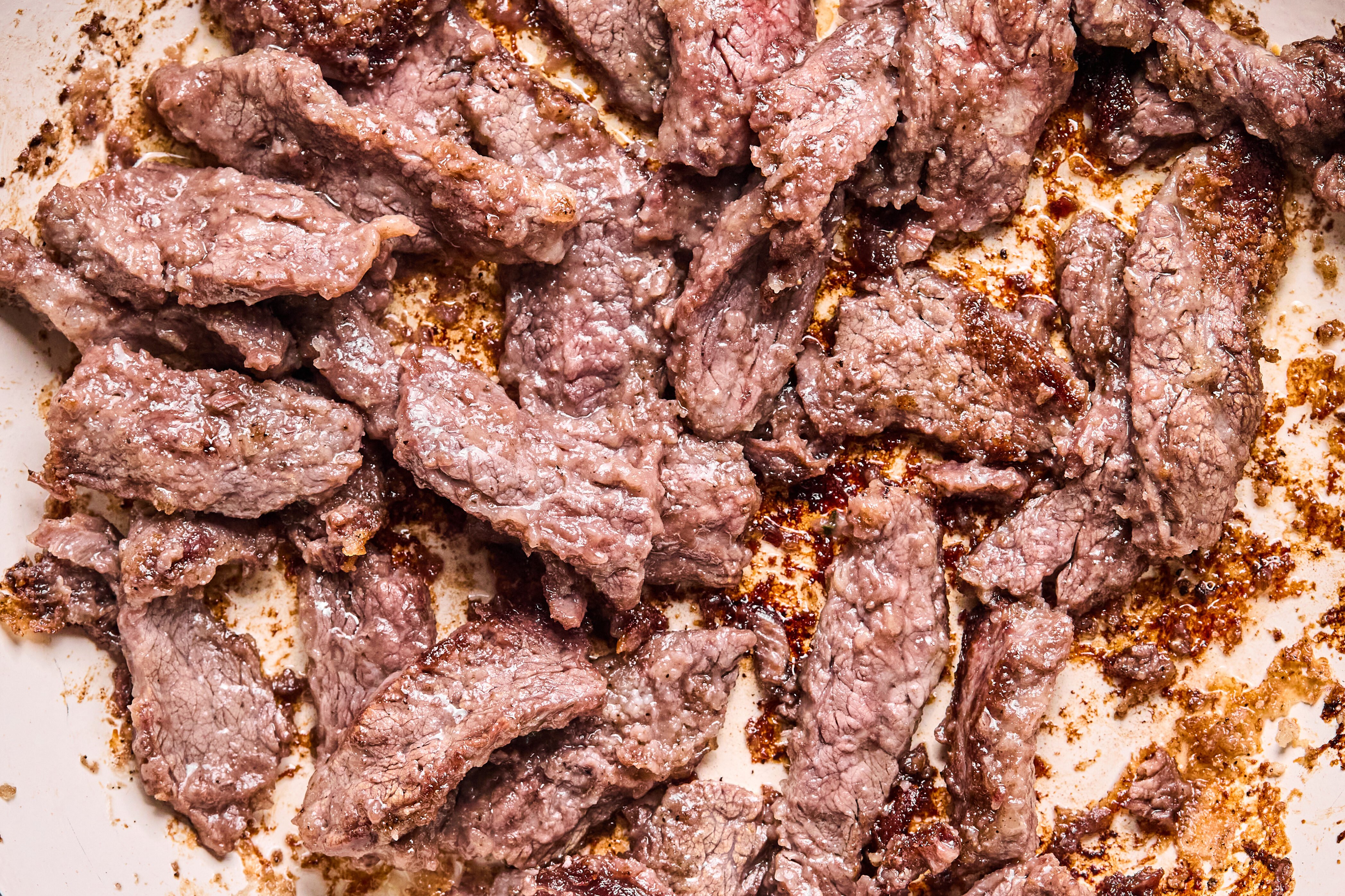 The flank steak sauting in a pan.