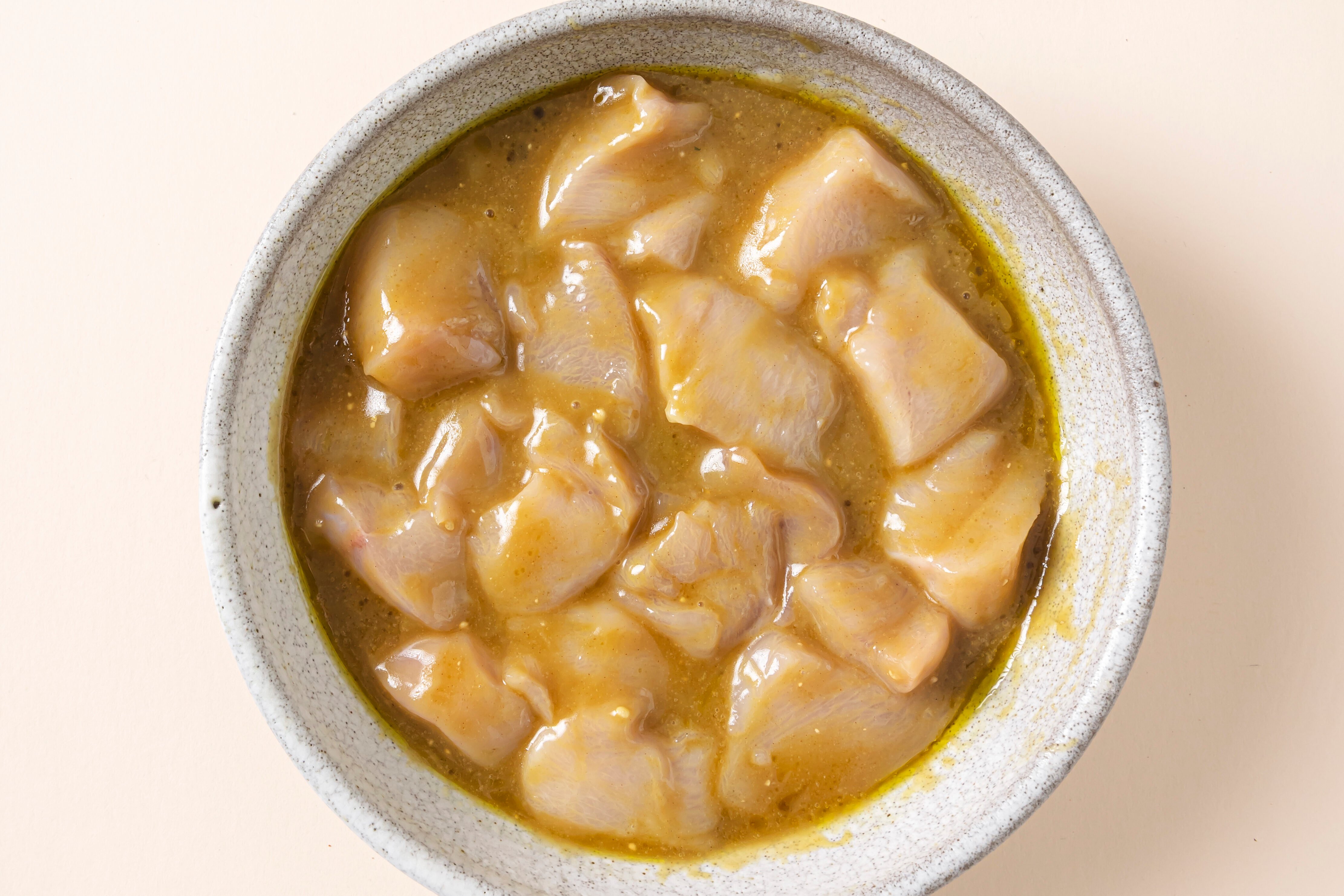 A bowl of chicken marinating in a bowl before cooking.