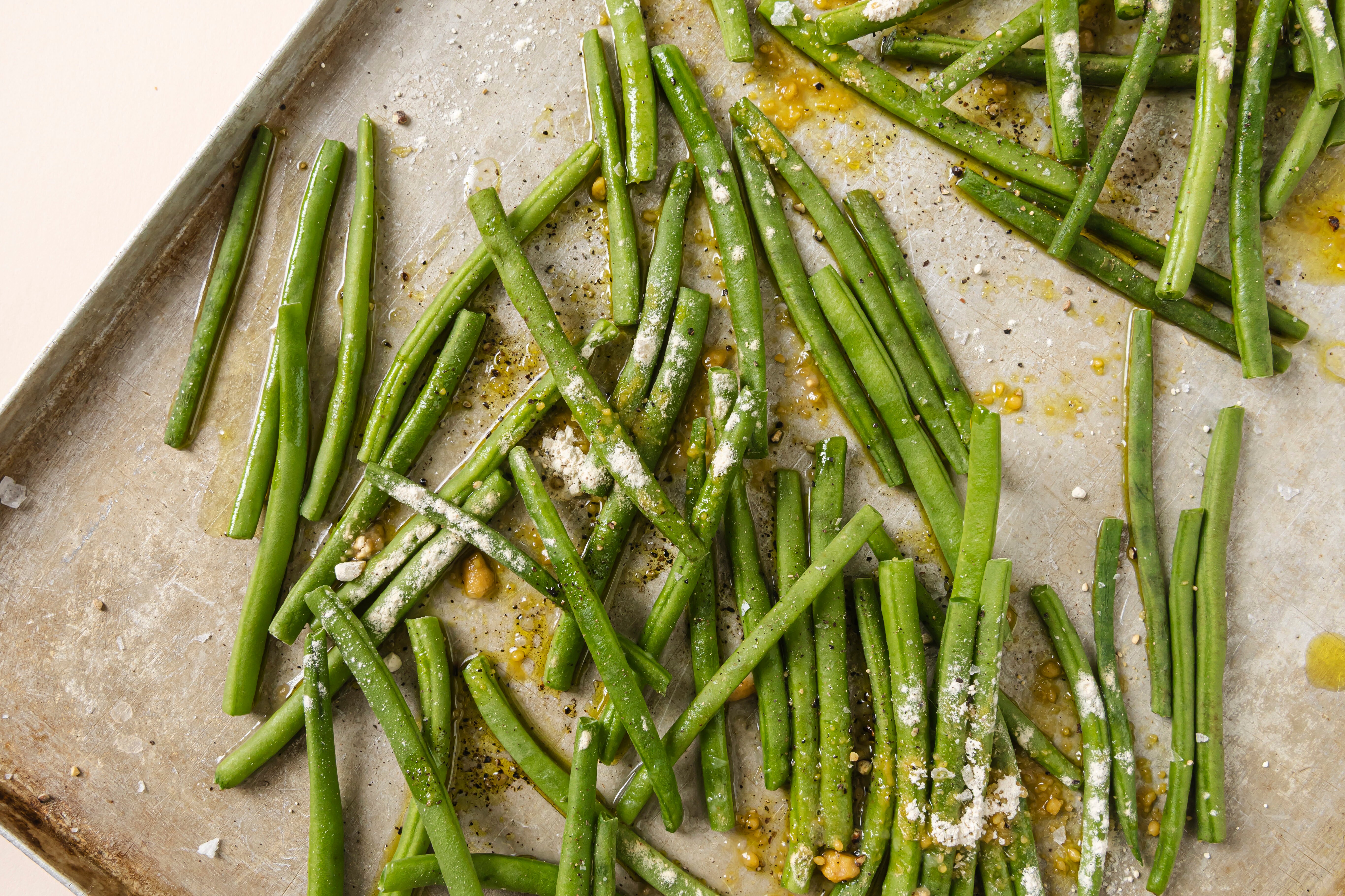 The green beans on a baking sheet before going into the oven.
