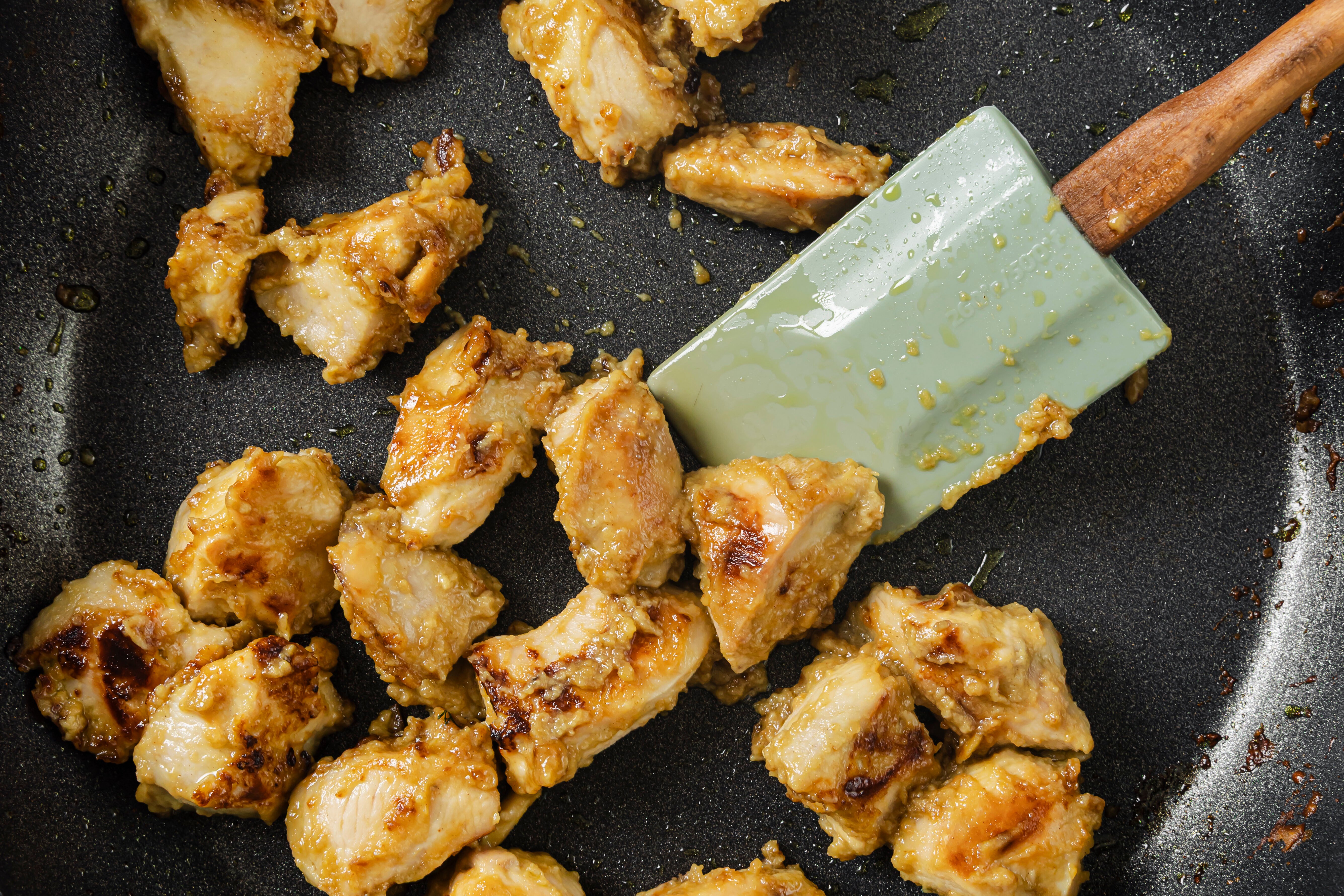 The chicken cooking in a pan.