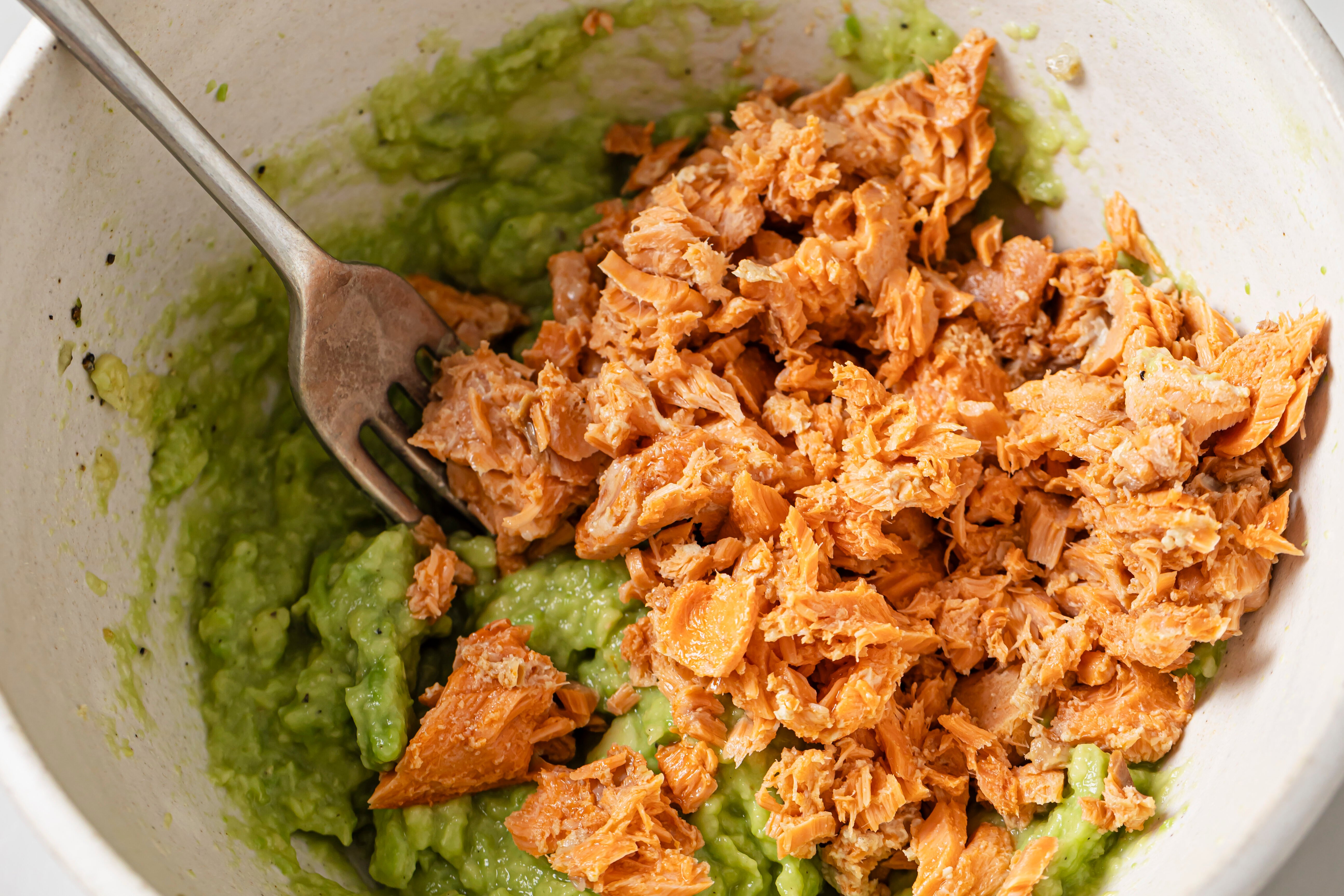 Canned salmon unmixed with mashed avocado. 