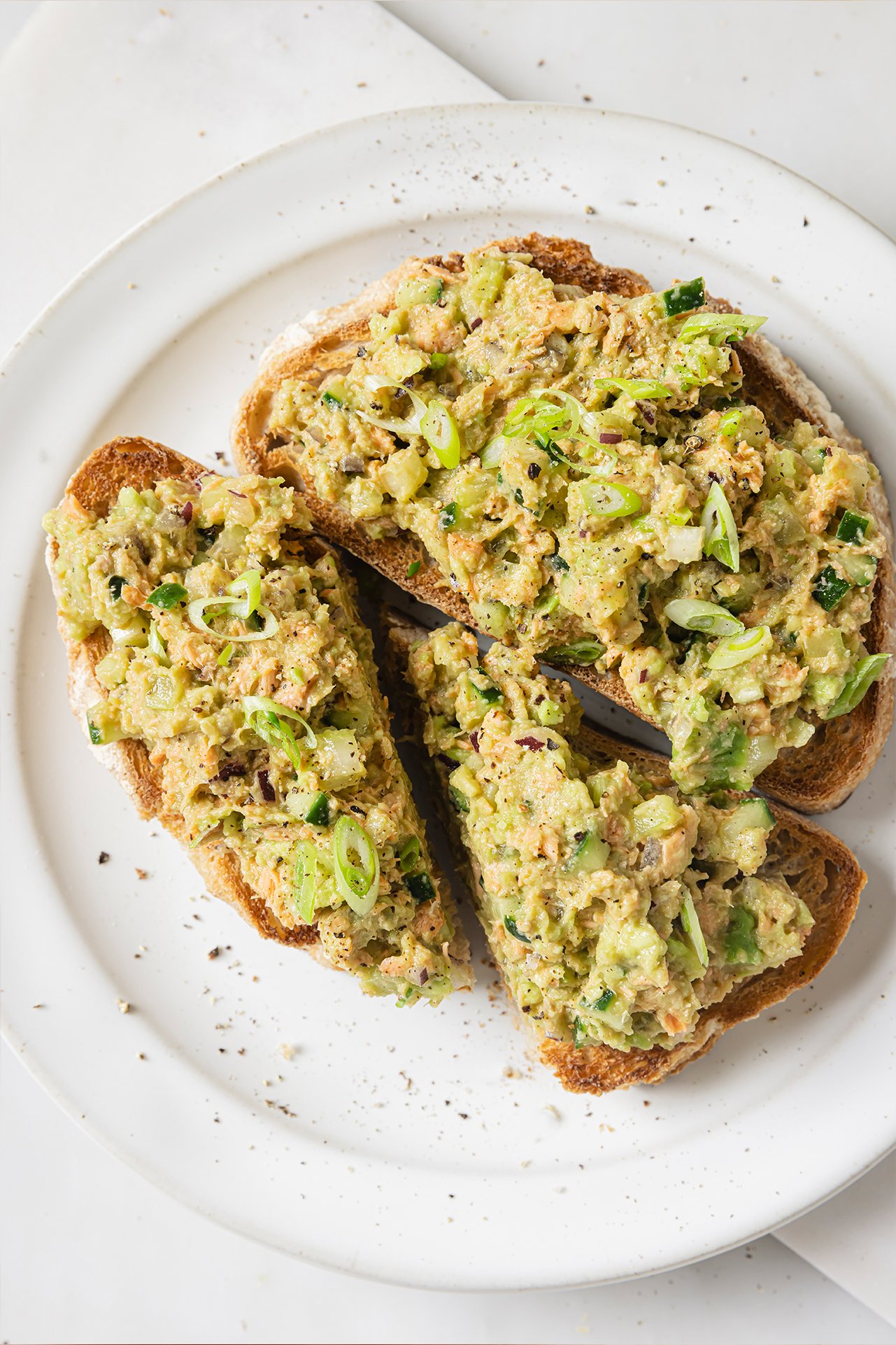 Avocado salmon salad on two slices of toast. 
