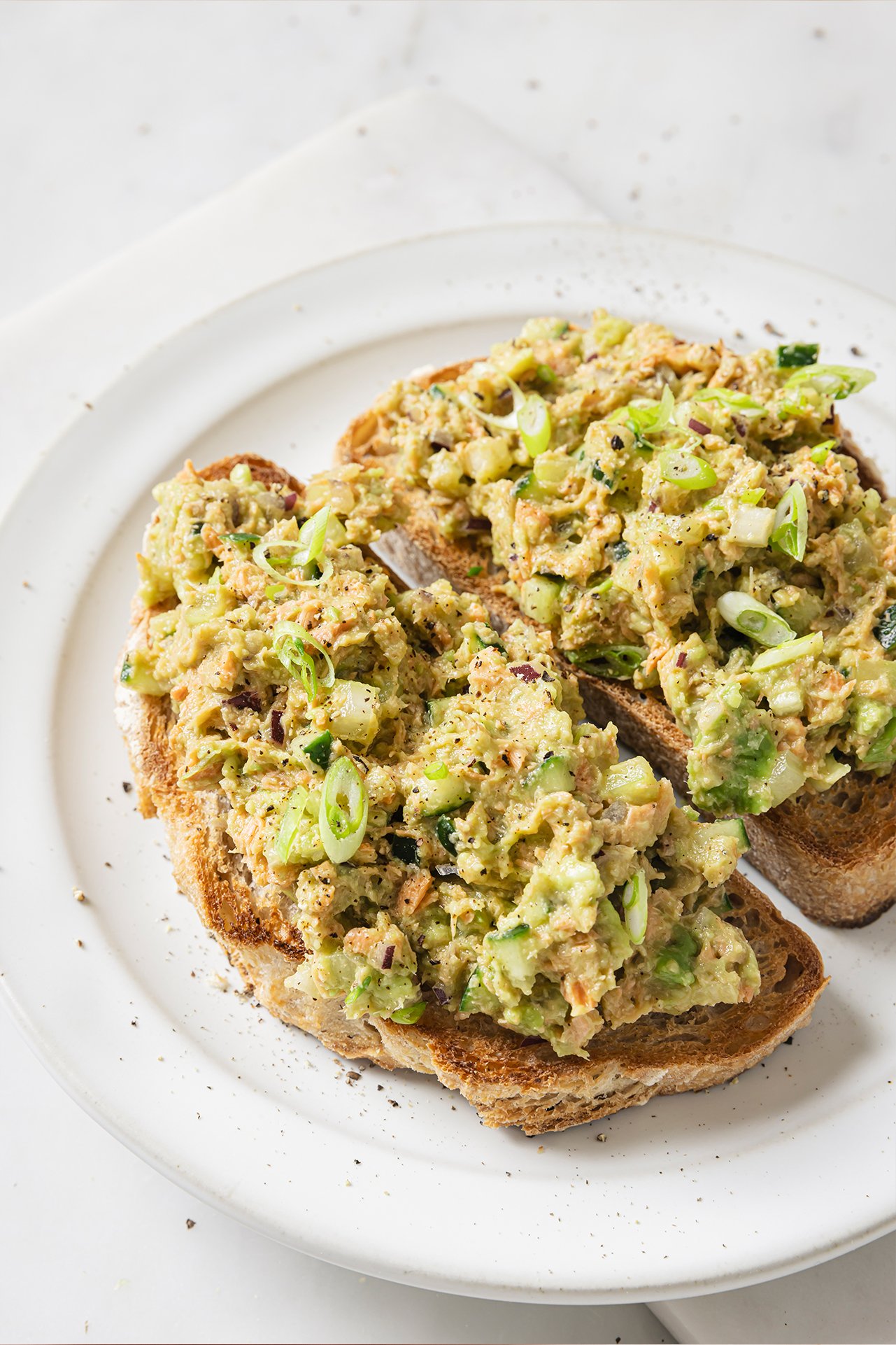 Avocado salmon salad on two whole slices of toast. 