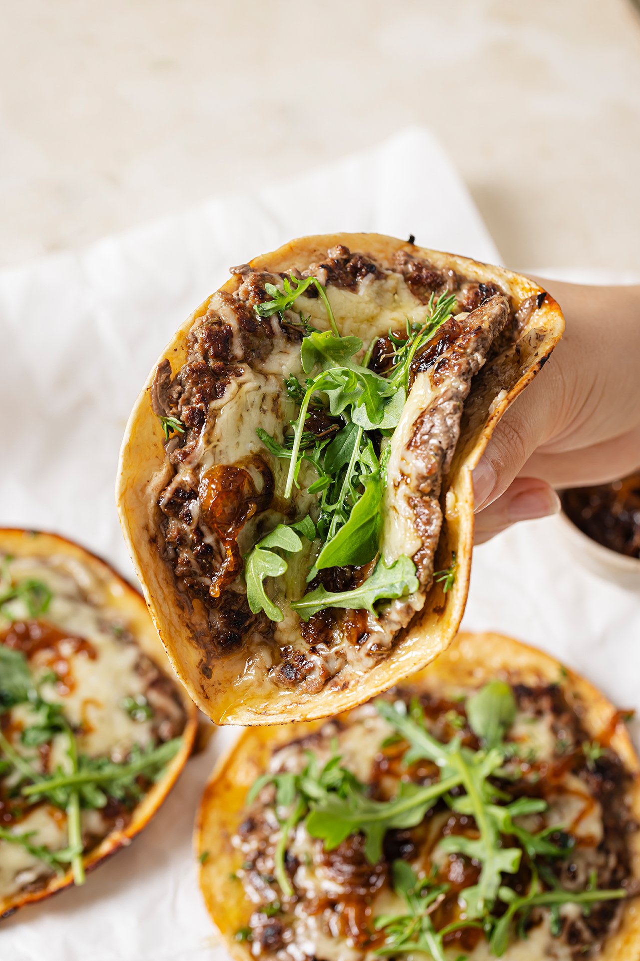 A french onion smashburger taco being held in a hand before eating.