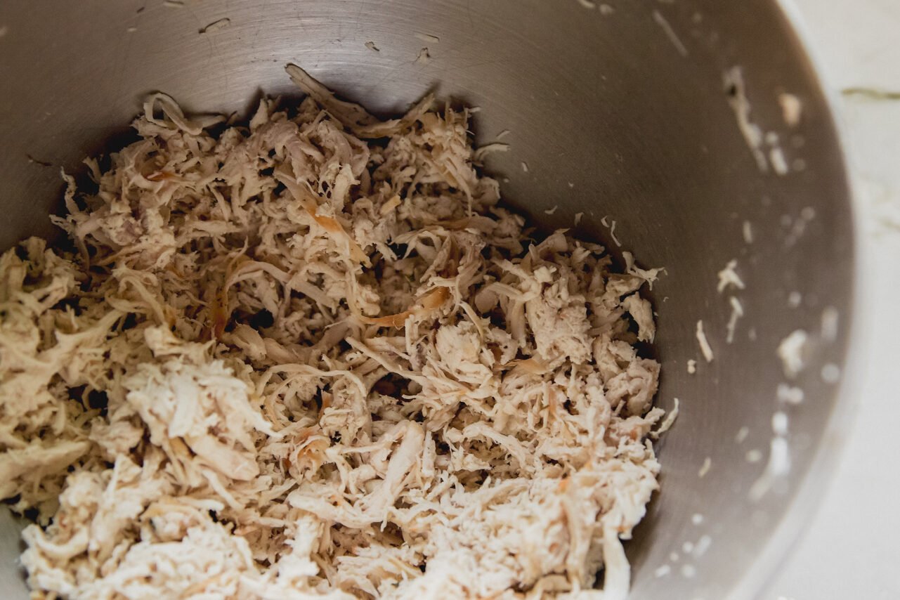 A bowl with shredded chicken in it.