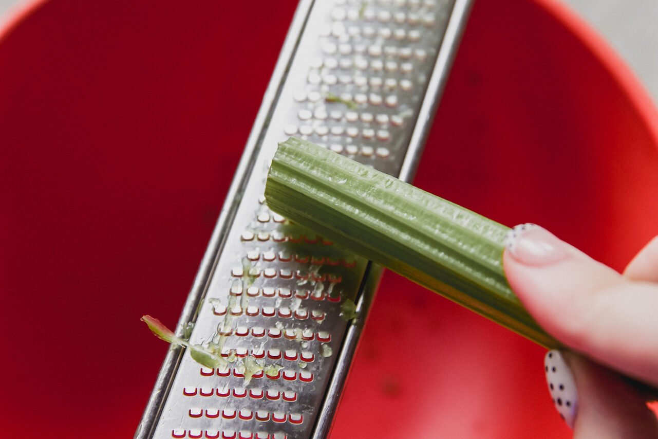 A microplane shredding celery into a bowl.