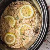 Slow cooker Greek chicken in the slow cooker topped with lemon slices.