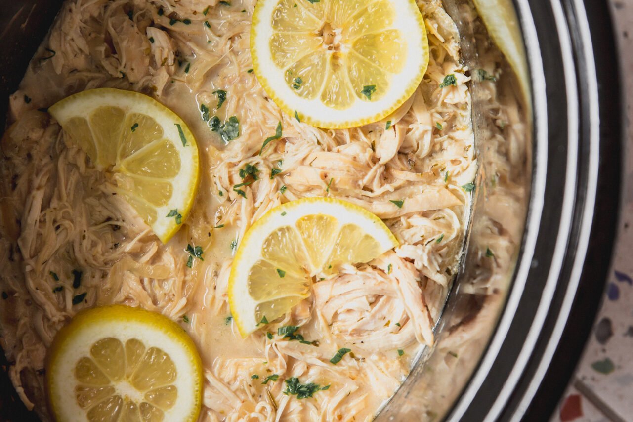 Slow cooker Greek chicken in the slow cooker topped with lemon slices.