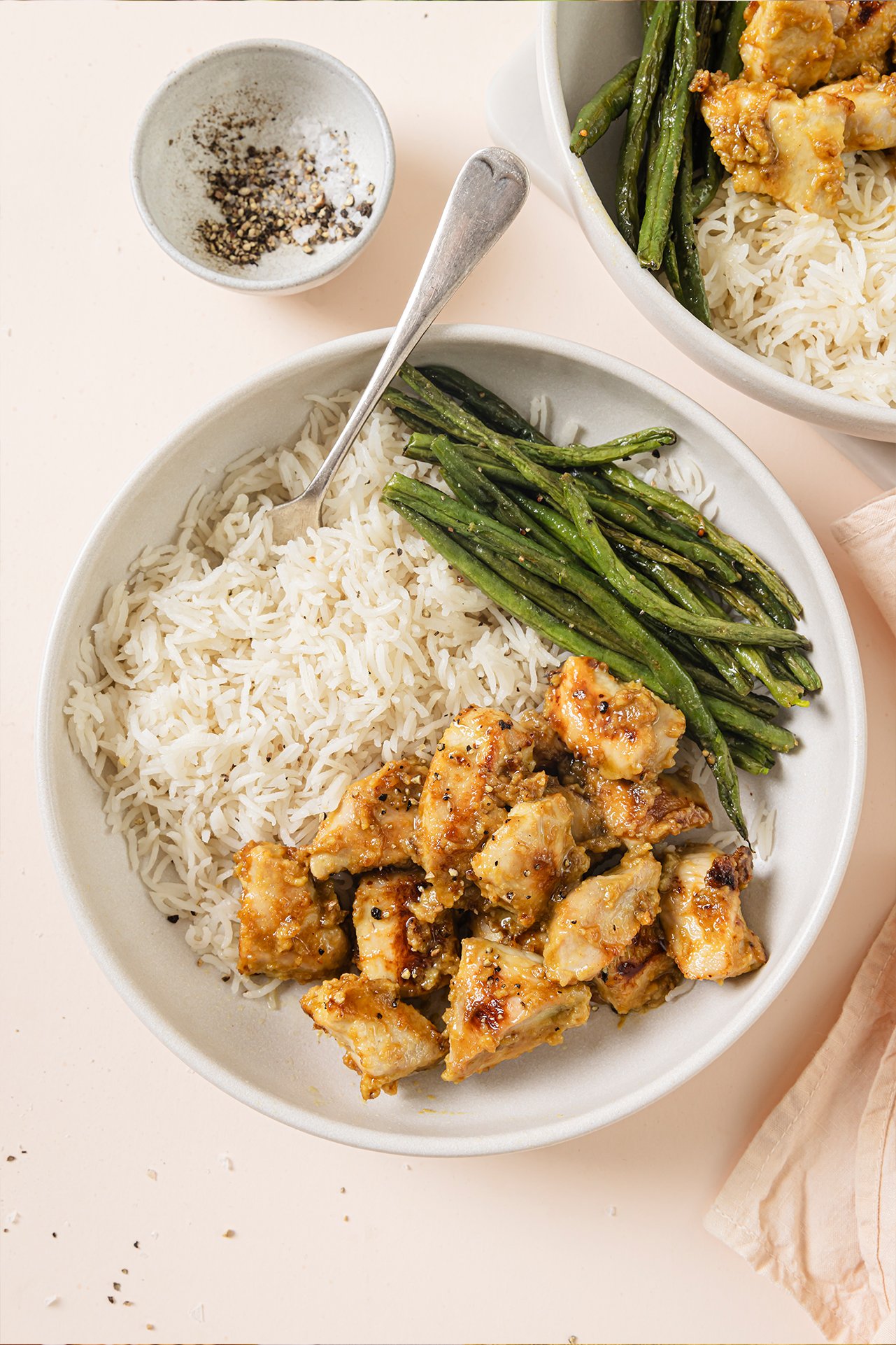 Honey mustard chicken bowls with a side of green beans and rice with a fork.