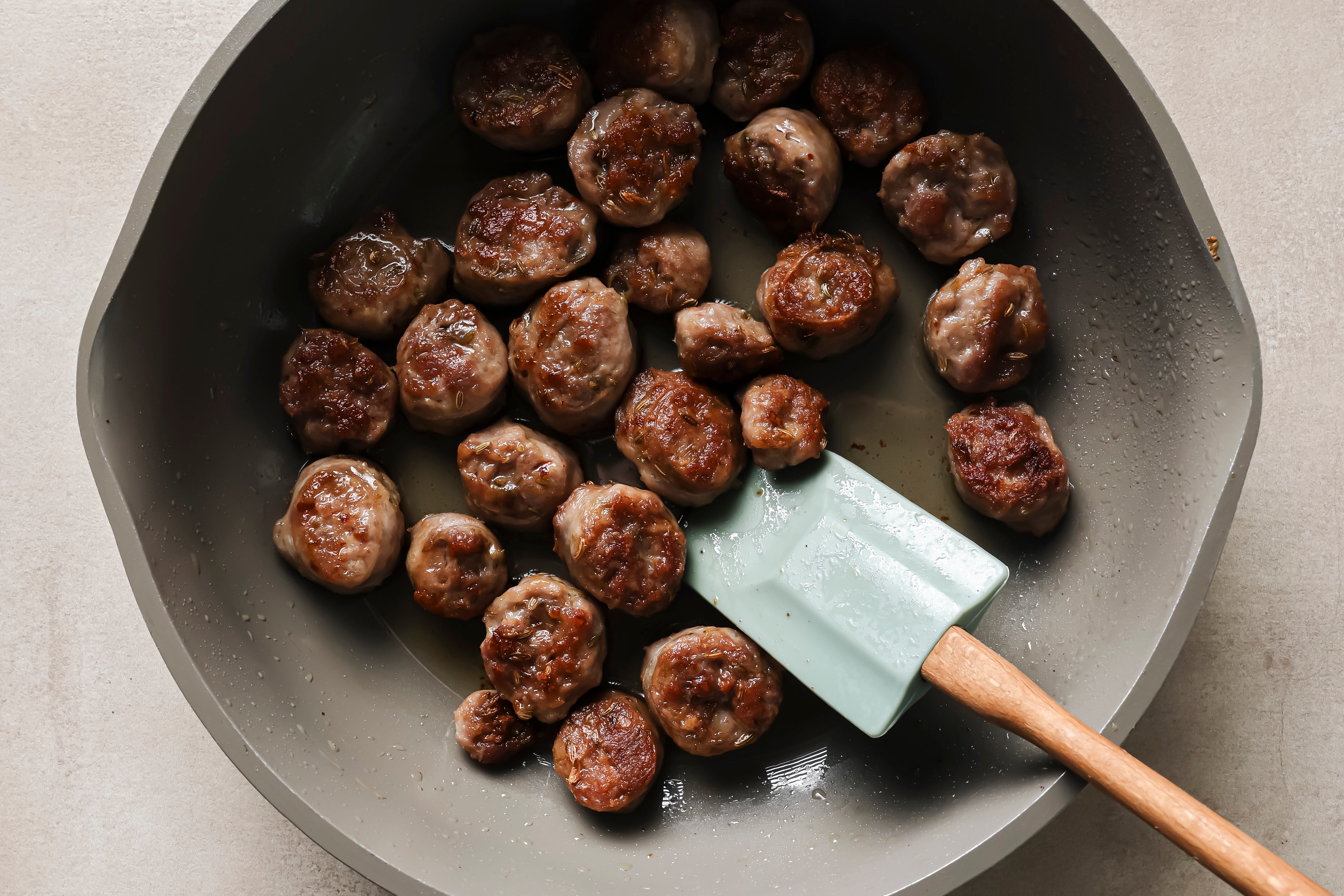 The sausage browning in a pan.