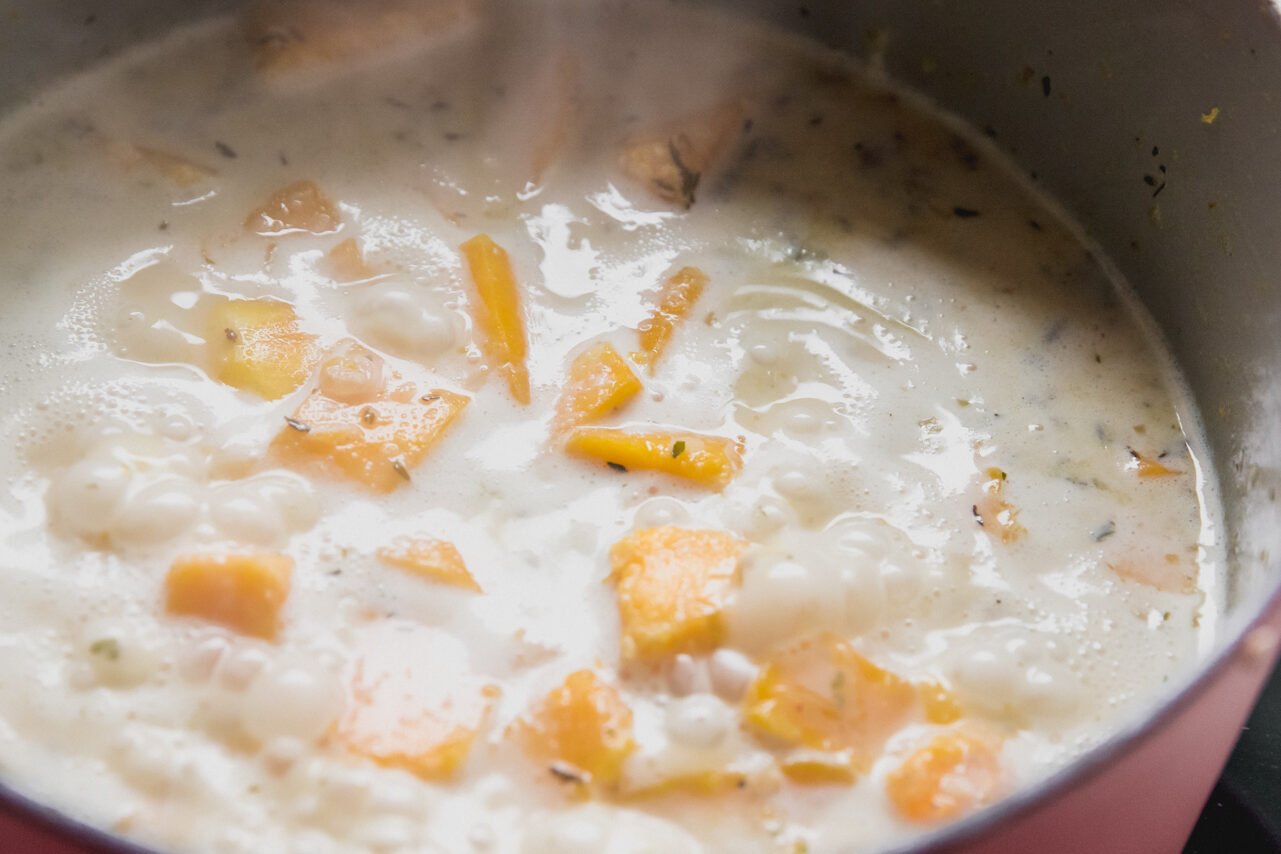 Butternut squash cooking coconut milk and chicken broth in a dutch oven.