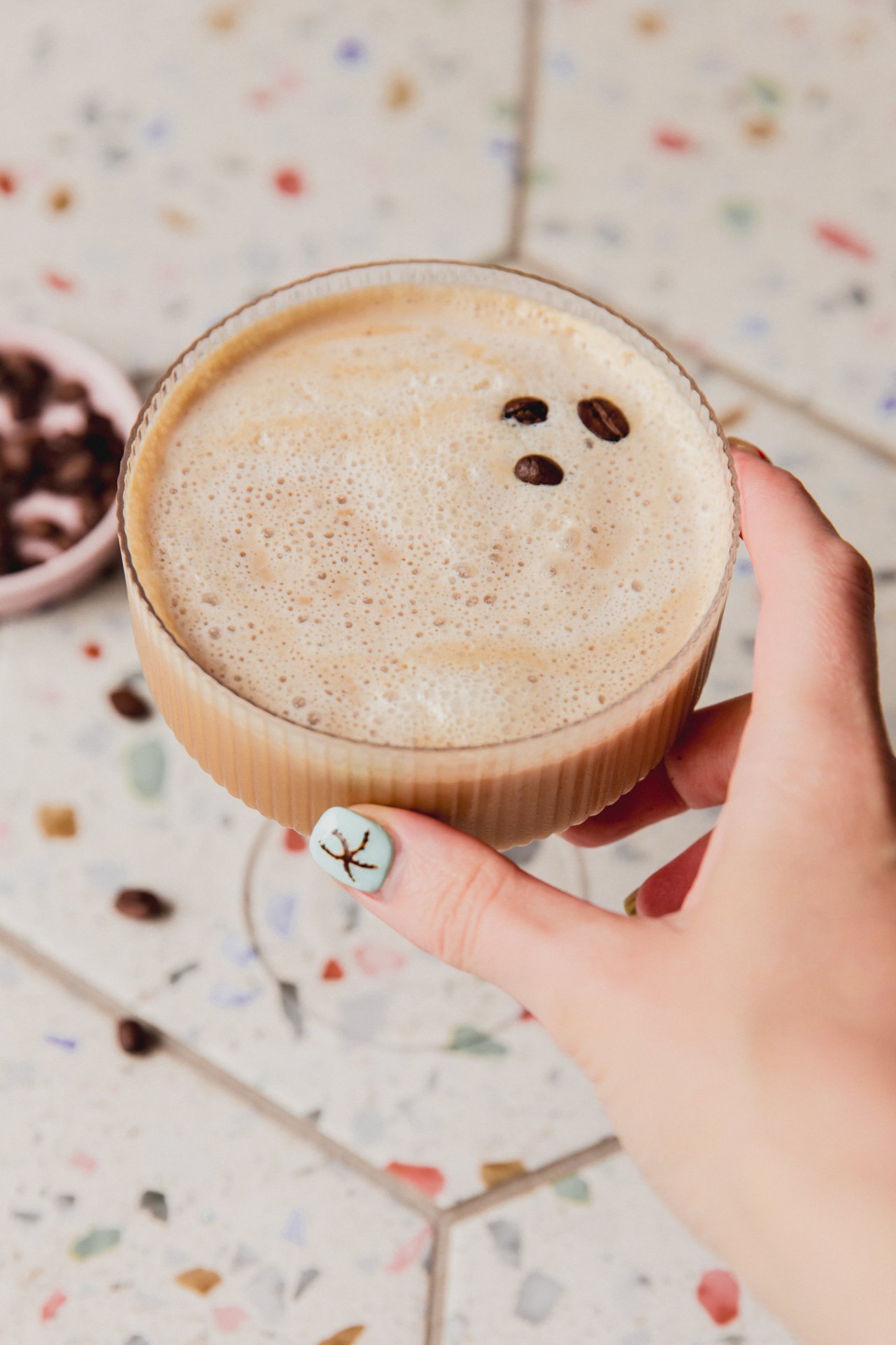 espresso martini mocktail being held in a cocktail glass.