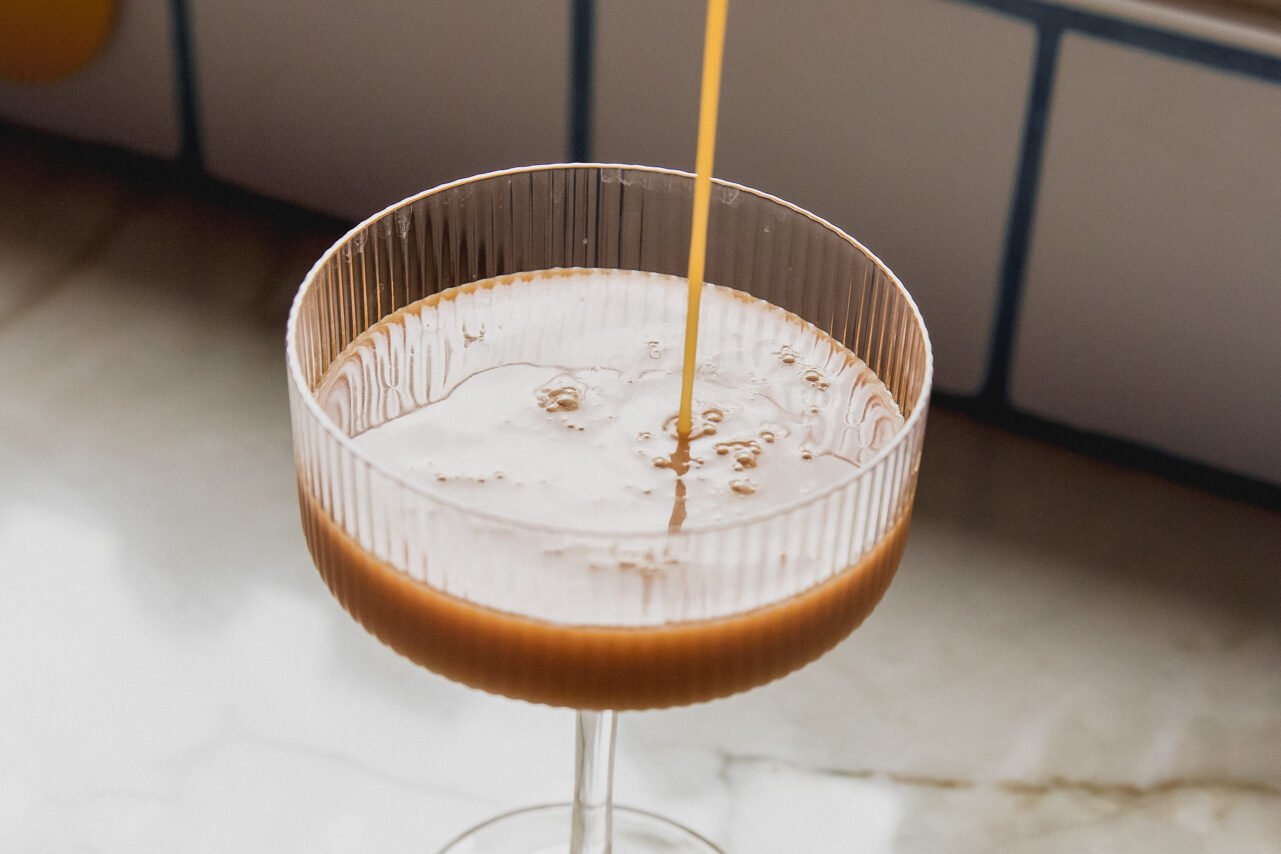 espresso martini mocktail pouring into a cocktail glass.