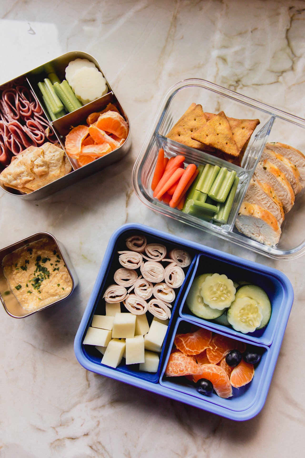 Three different lunchboxes packed with different foods on a counter.
