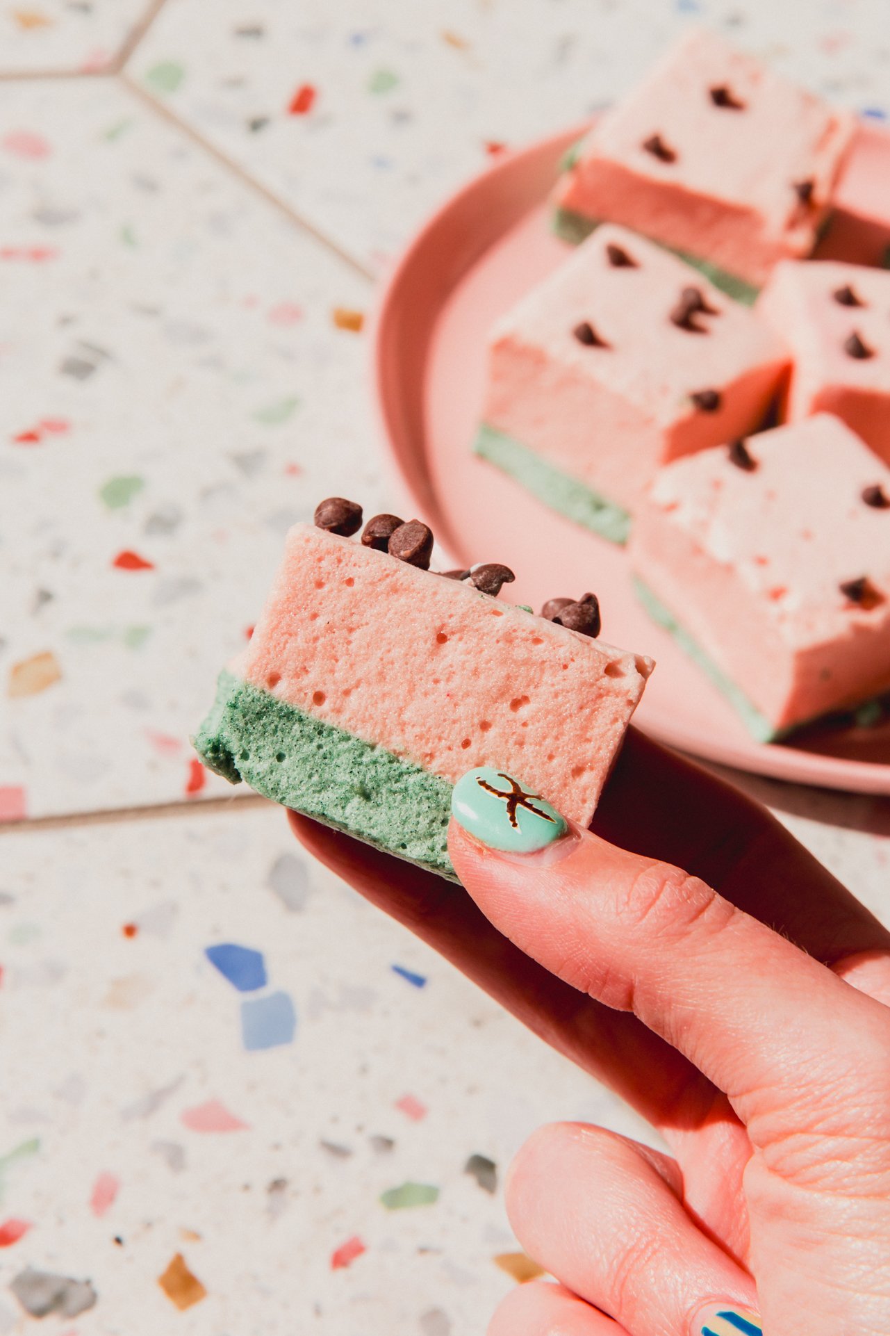 A hand holding one watermelon marshmallow before eating.