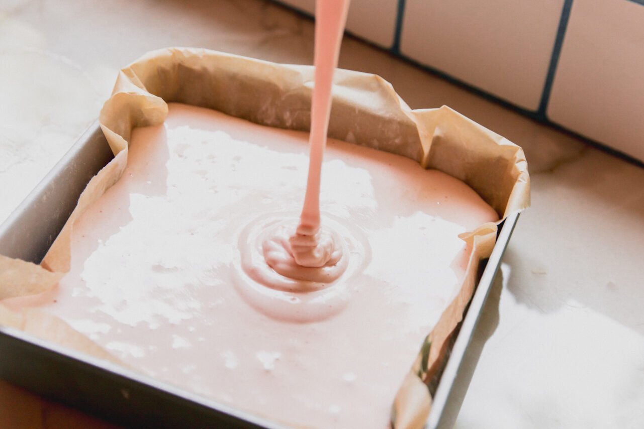 The pink layer being poured on top of the green layer before solidifying. 