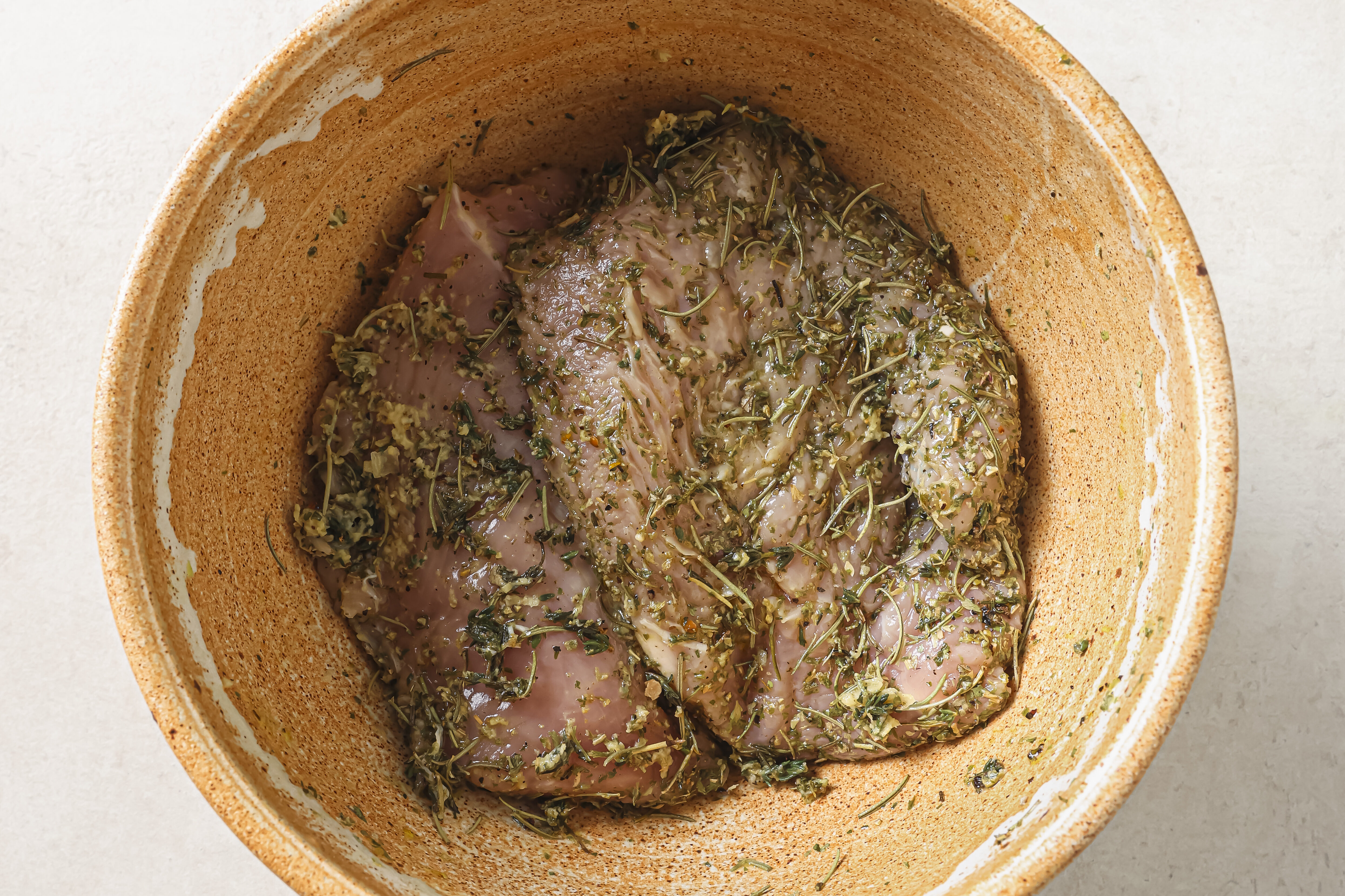 Turkey tenderloin marinating in a bowl.