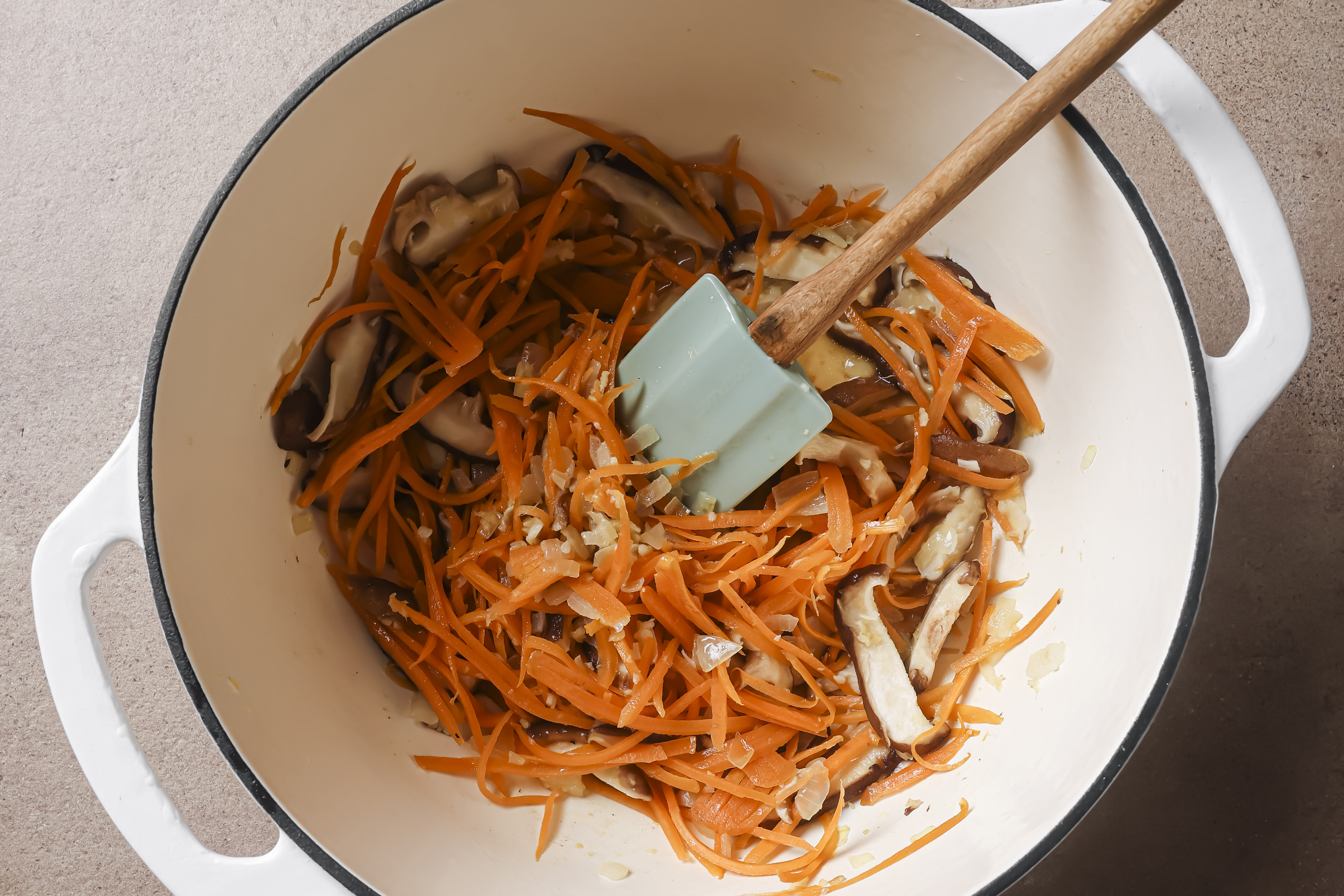 Onion , carrots and mushrooms sautéing in a pot.
