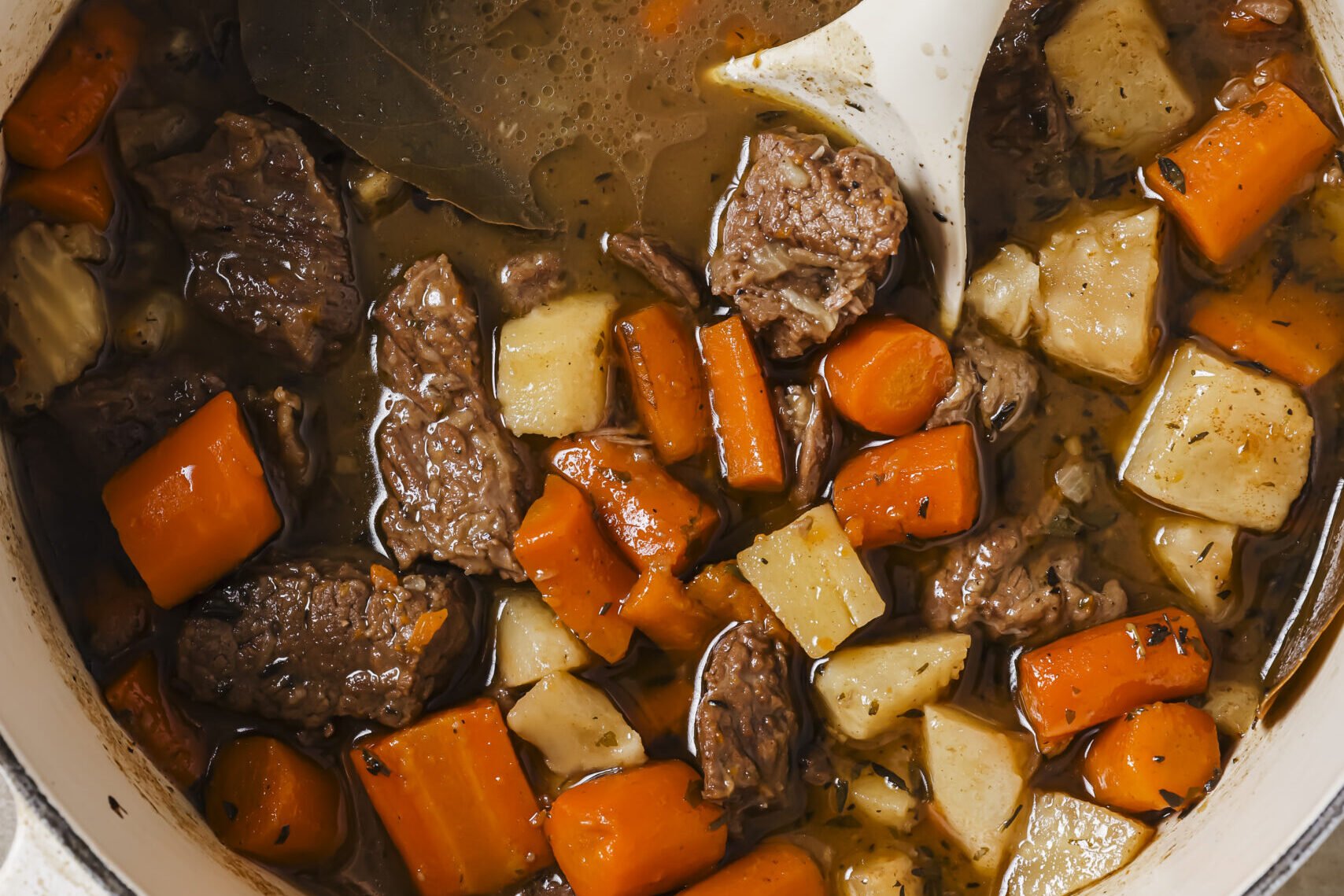 Dutch oven beef stew in a pot, with a spoon.