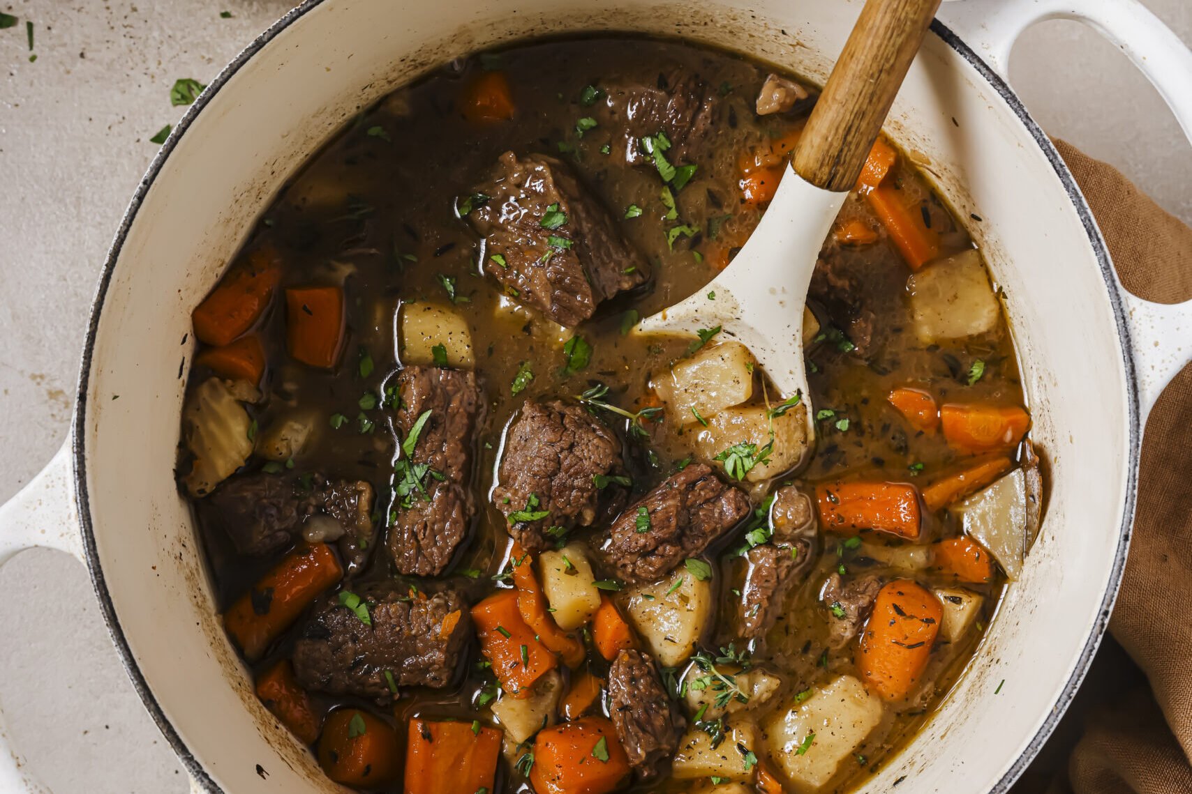 Dutch oven beef stew in a pot, topped with herbs.