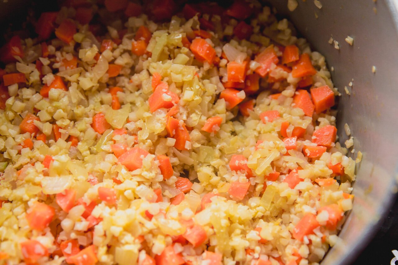 Carrots, celery and cauliflower rice sauteed in a pot.