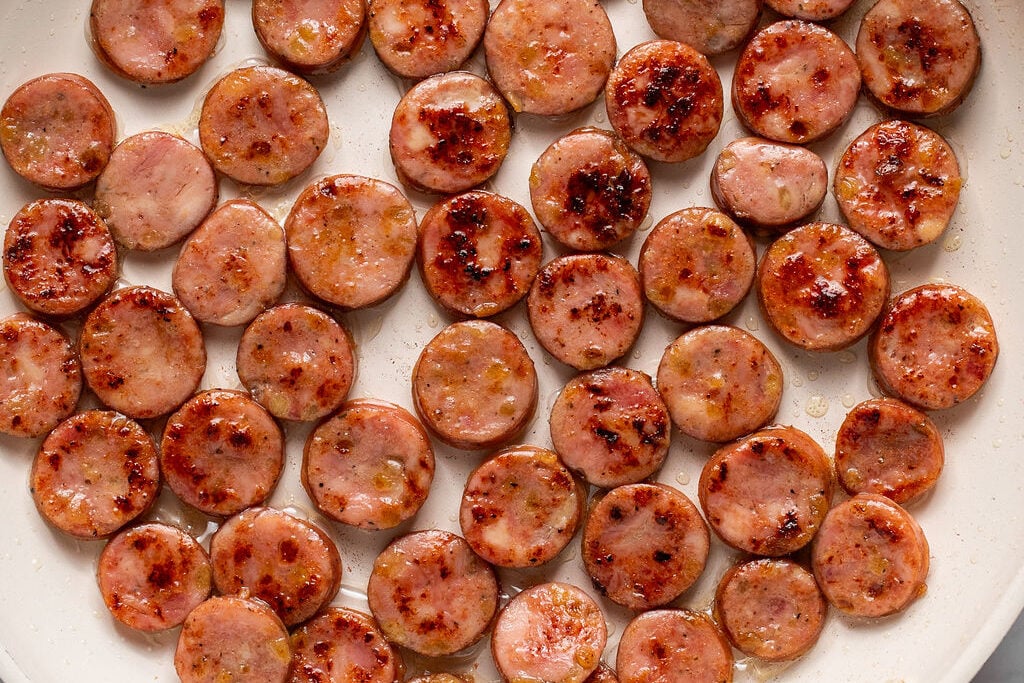 Uncooked sliced chicken sausage uncooked in a pan.