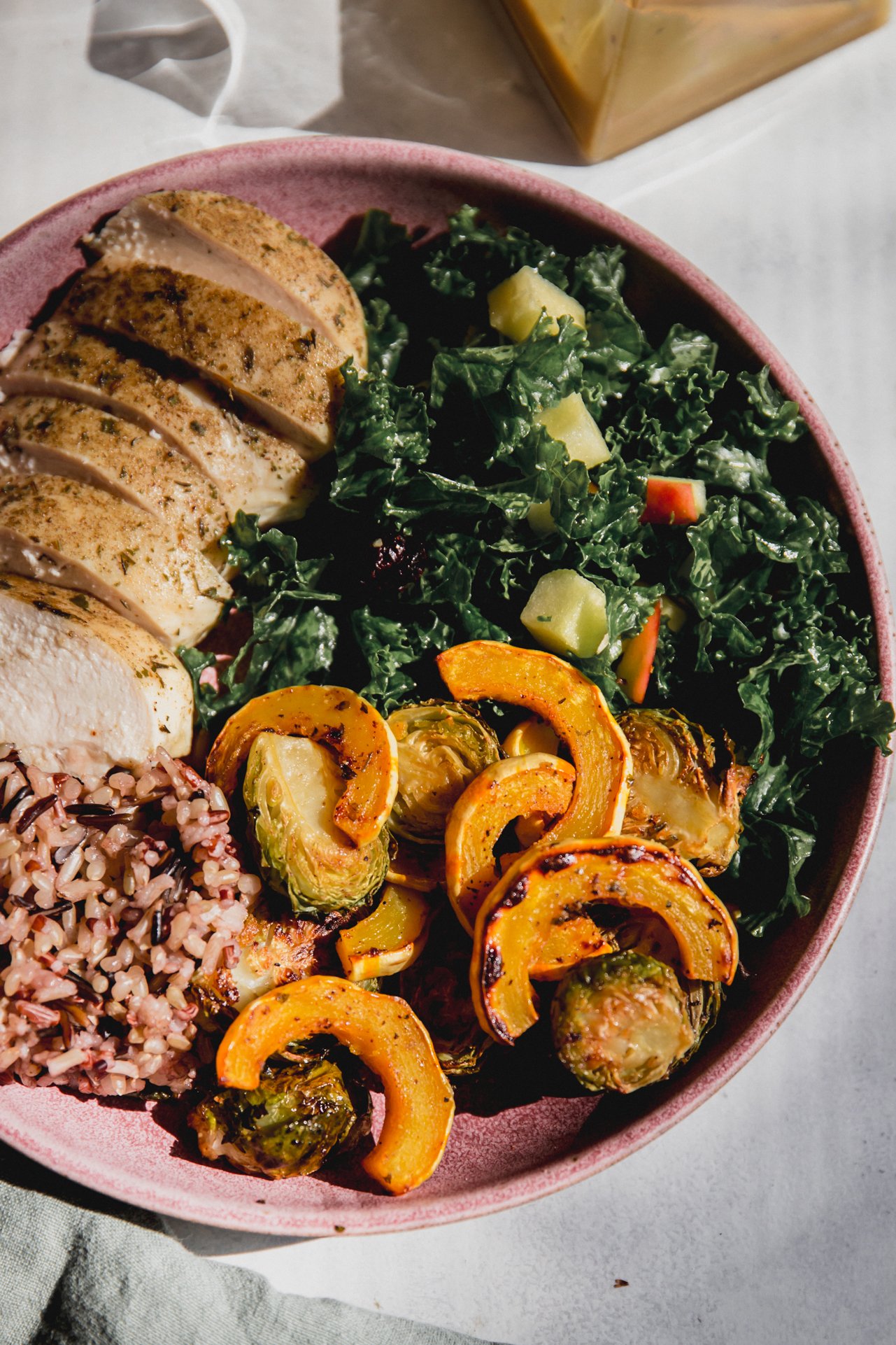 A roasted squash harvest bowl with kale salad, chicken, squash, and rice.